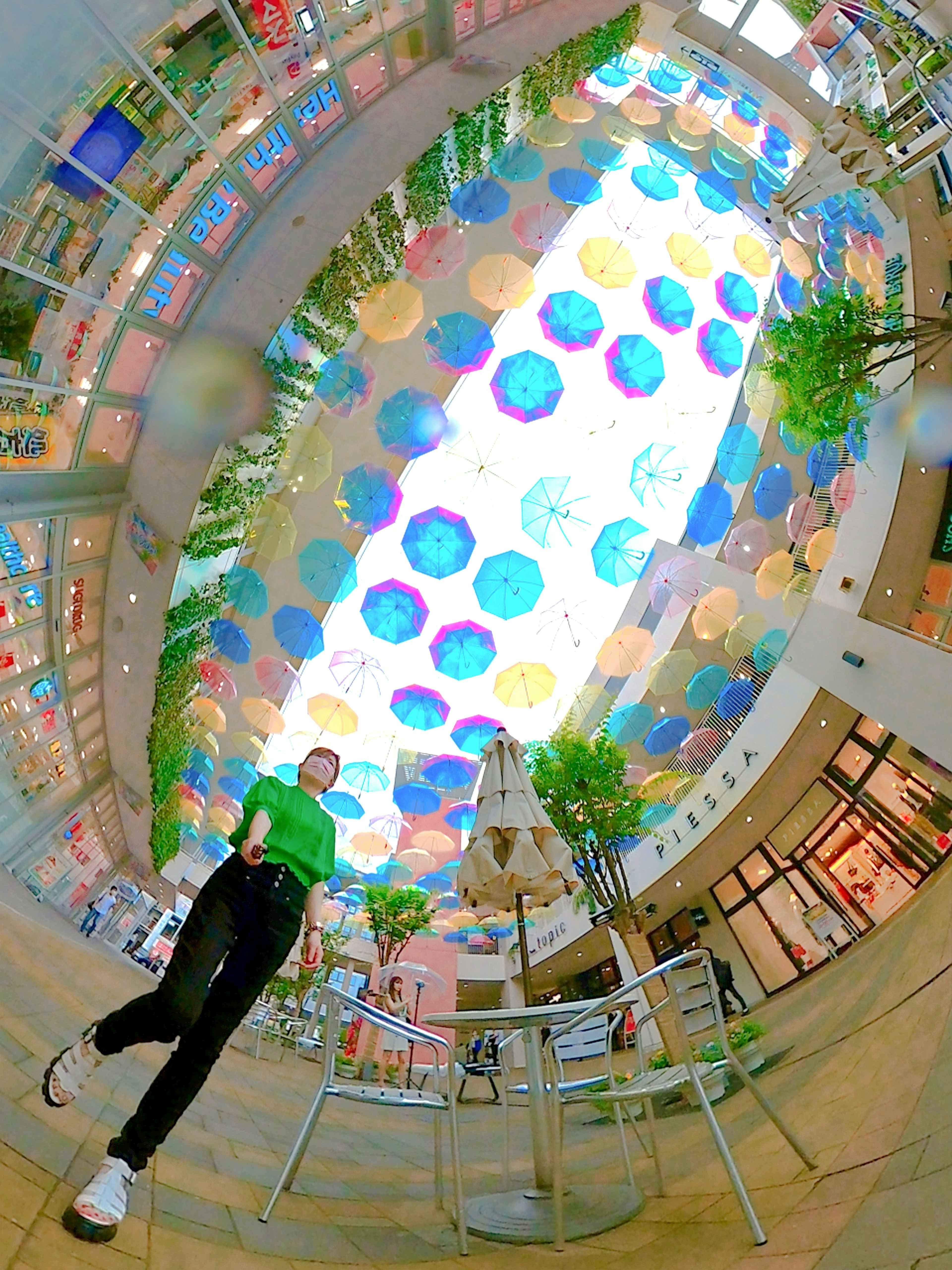 Person walking in an indoor space with colorful umbrellas overhead