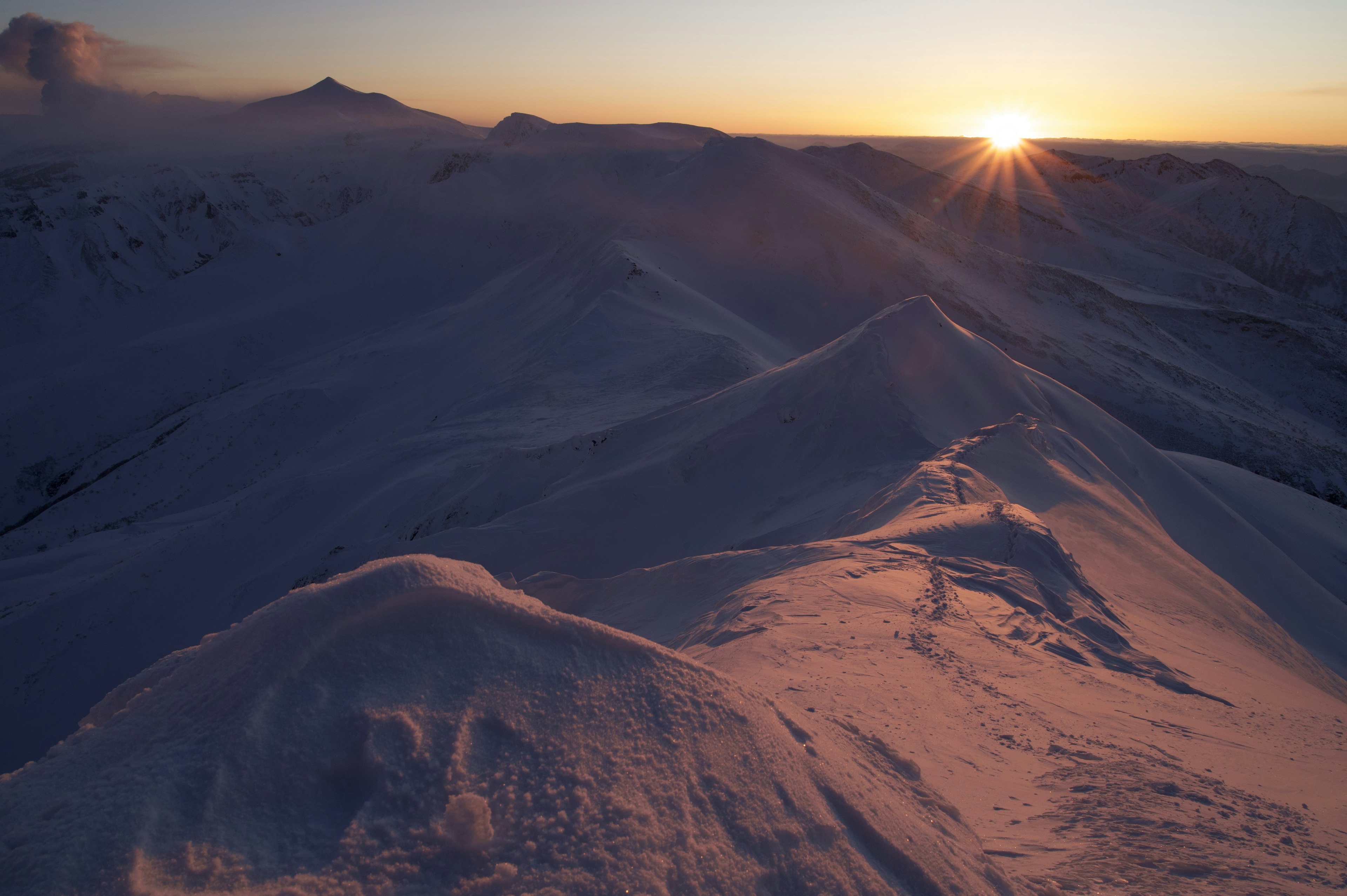 Ridges de montagnes enneigées au coucher de soleil