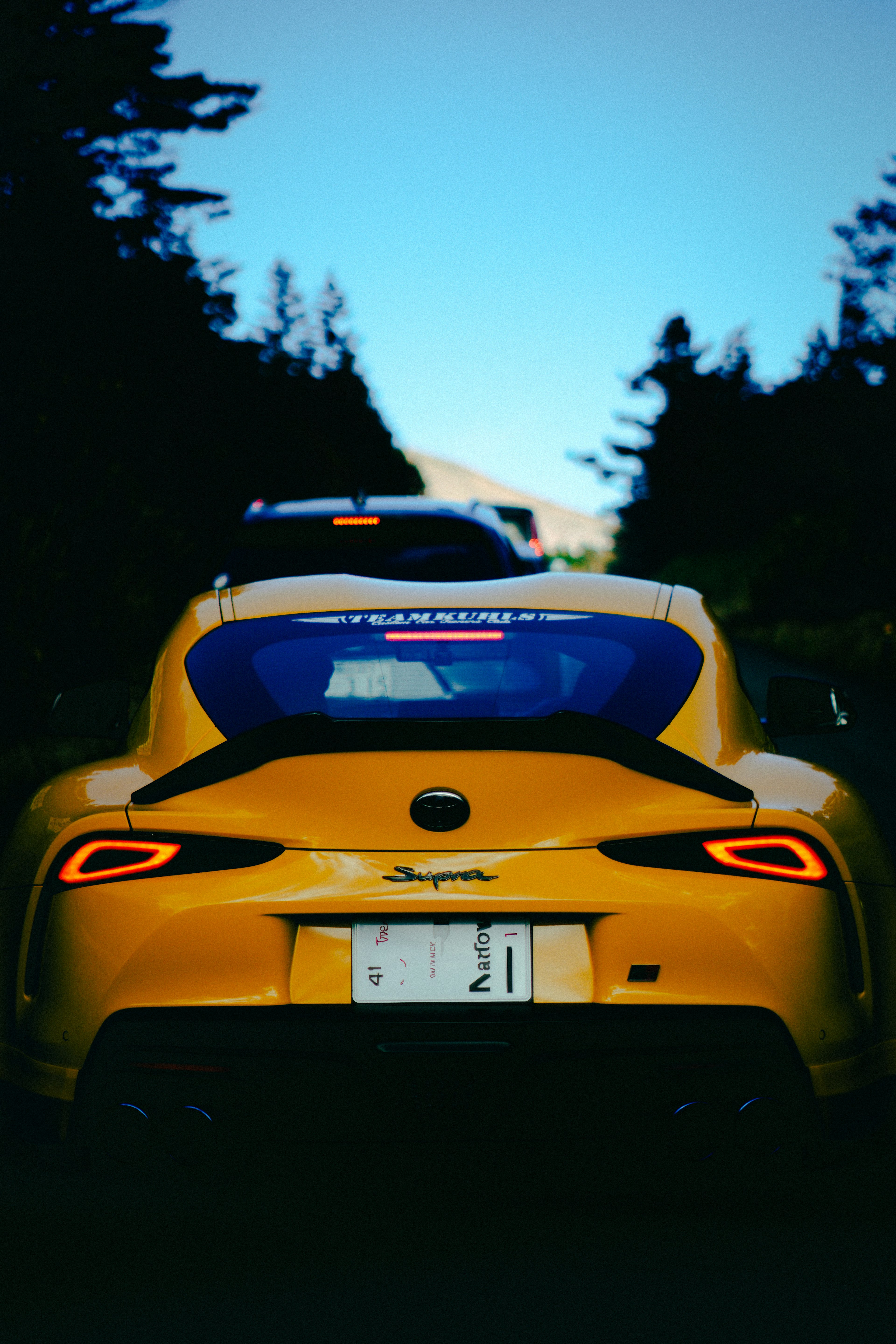 Rear view of a yellow sports car on a scenic road