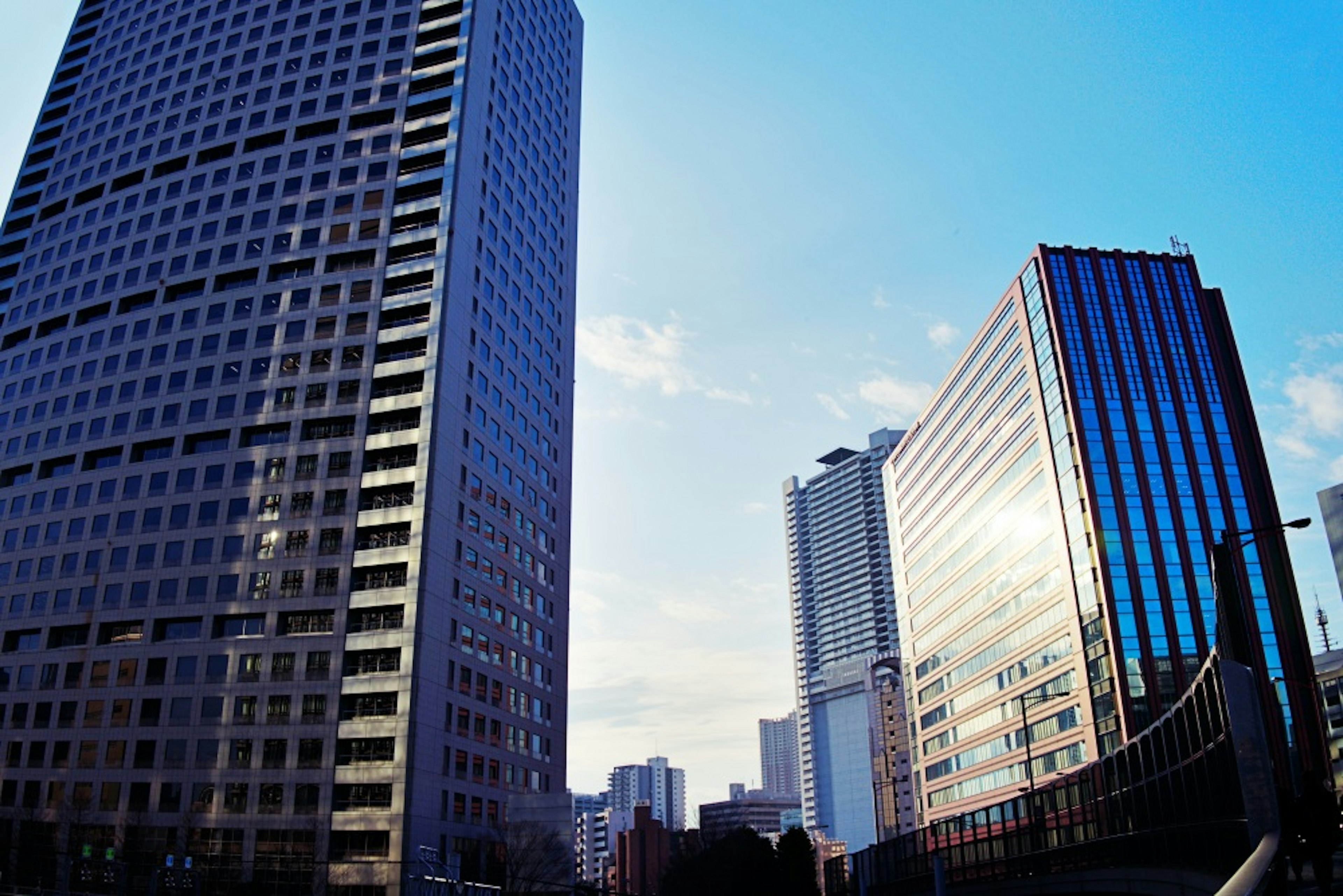 Cityscape featuring tall buildings under a blue sky with clouds