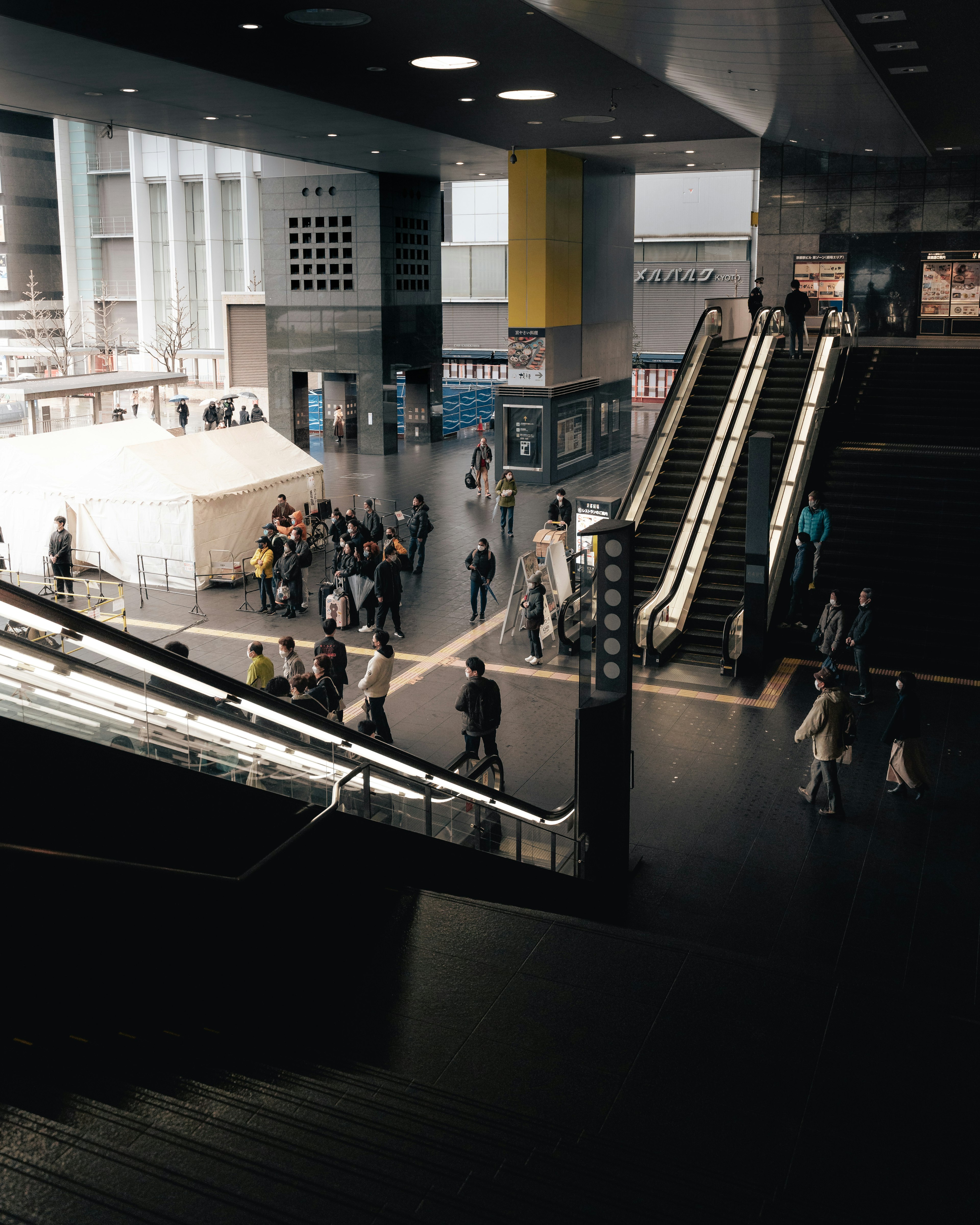 Busy interior of a train station featuring escalators and many people