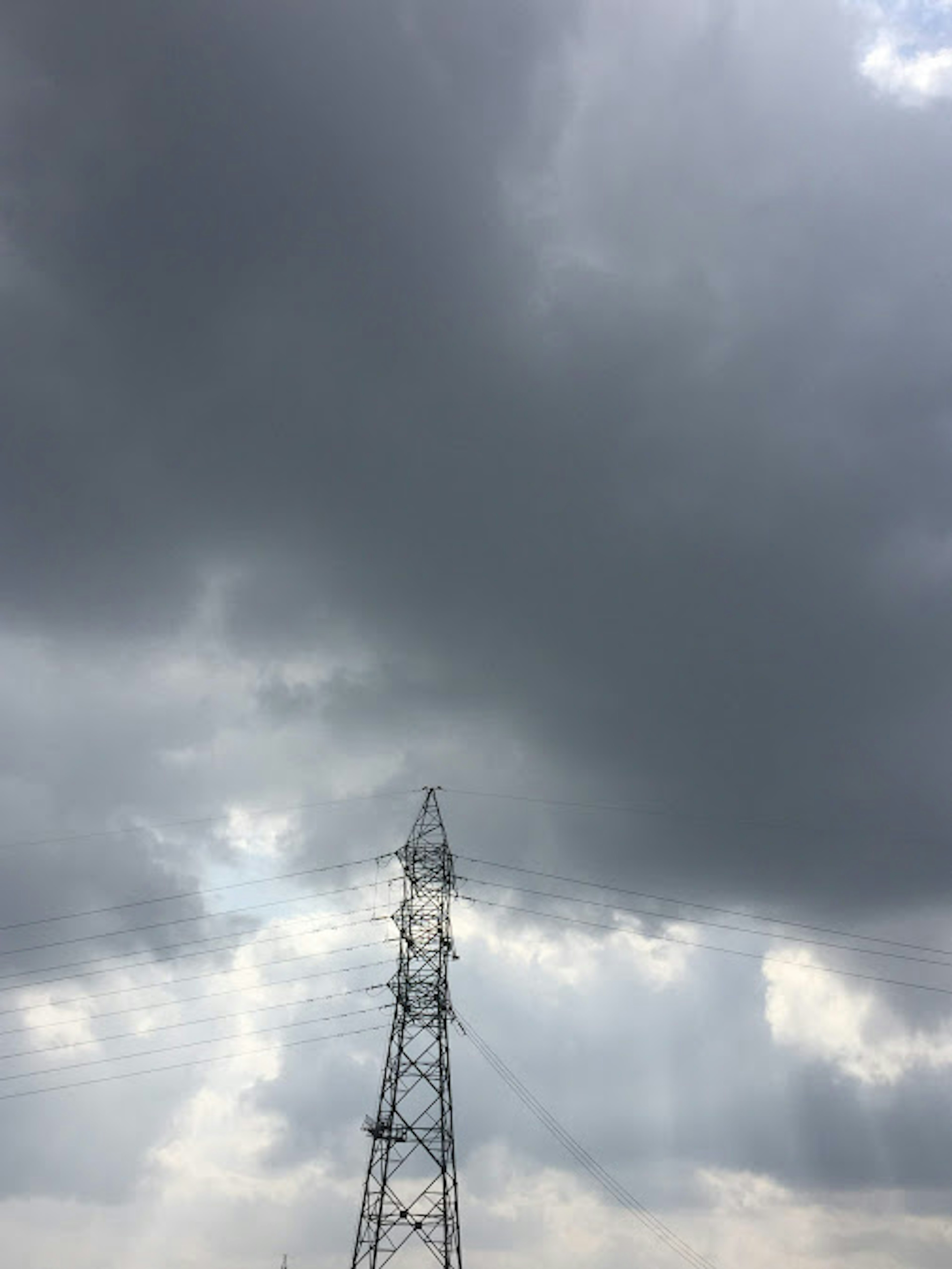 Imagen de una torre eléctrica bajo nubes gris oscuro