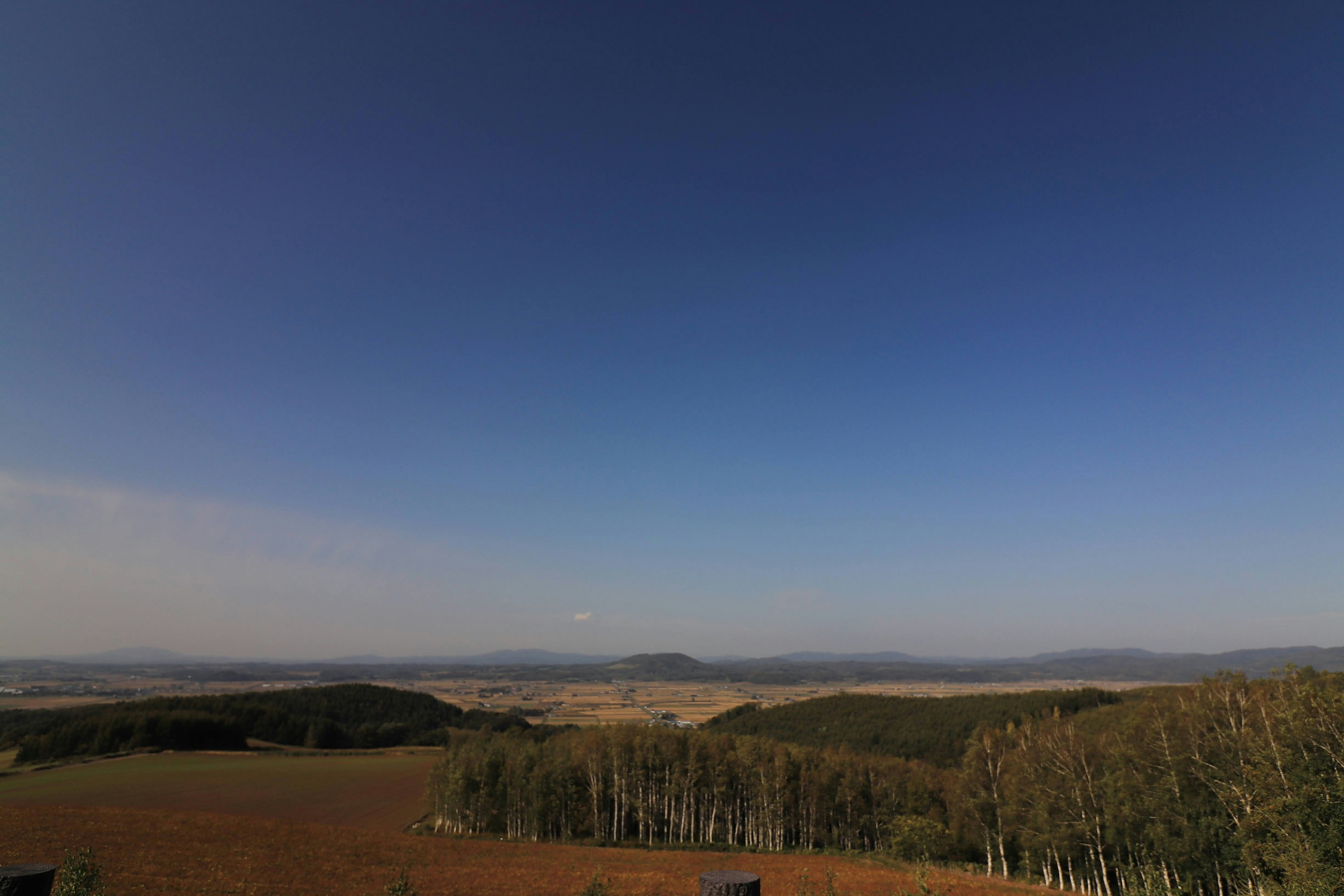 Vue panoramique avec un ciel bleu et un vaste paysage de collines basses et de champs ouverts