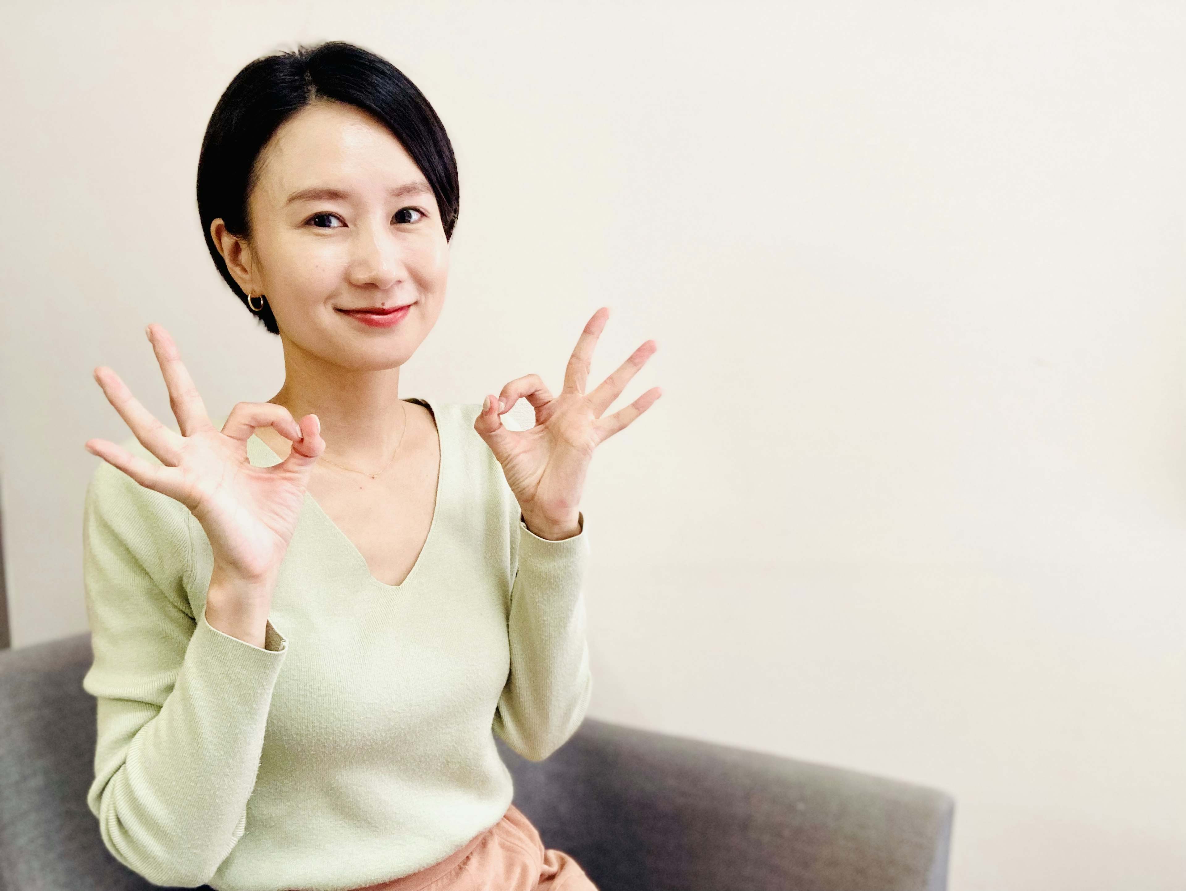 Young woman in green sweater smiling and making hand gestures