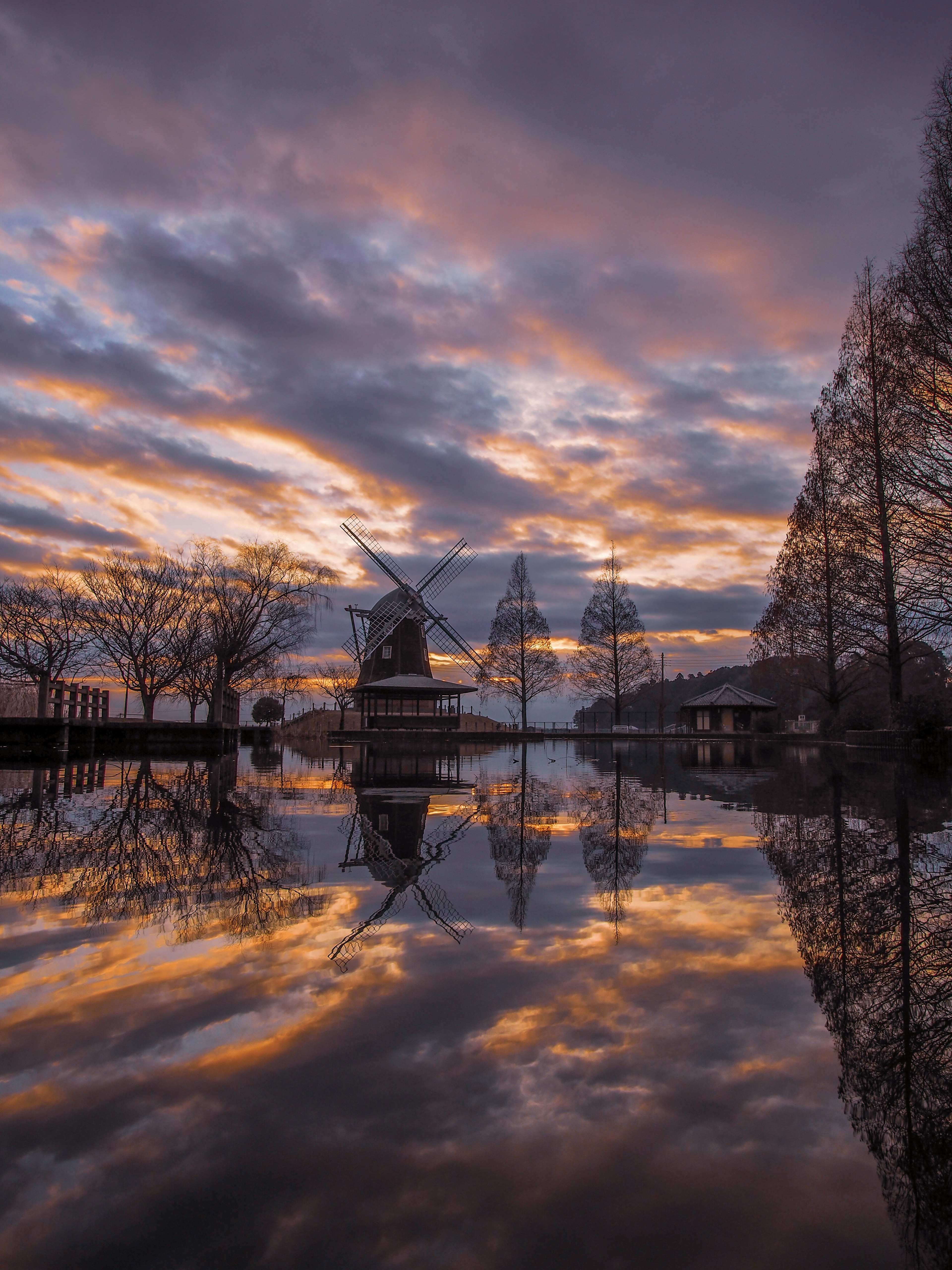 Paysage magnifique d'un moulin à vent reflété dans l'eau sous un ciel au coucher du soleil