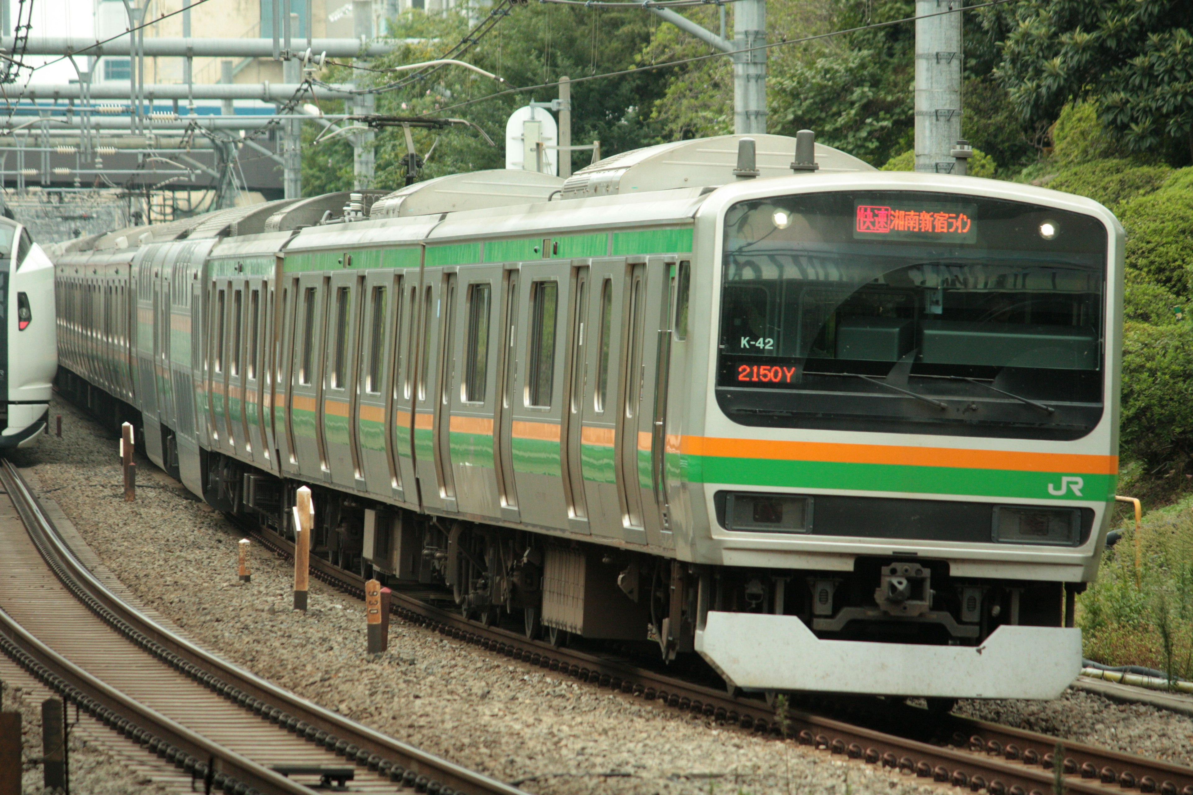 緑とオレンジのストライプが特徴の日本の電車が線路を走る