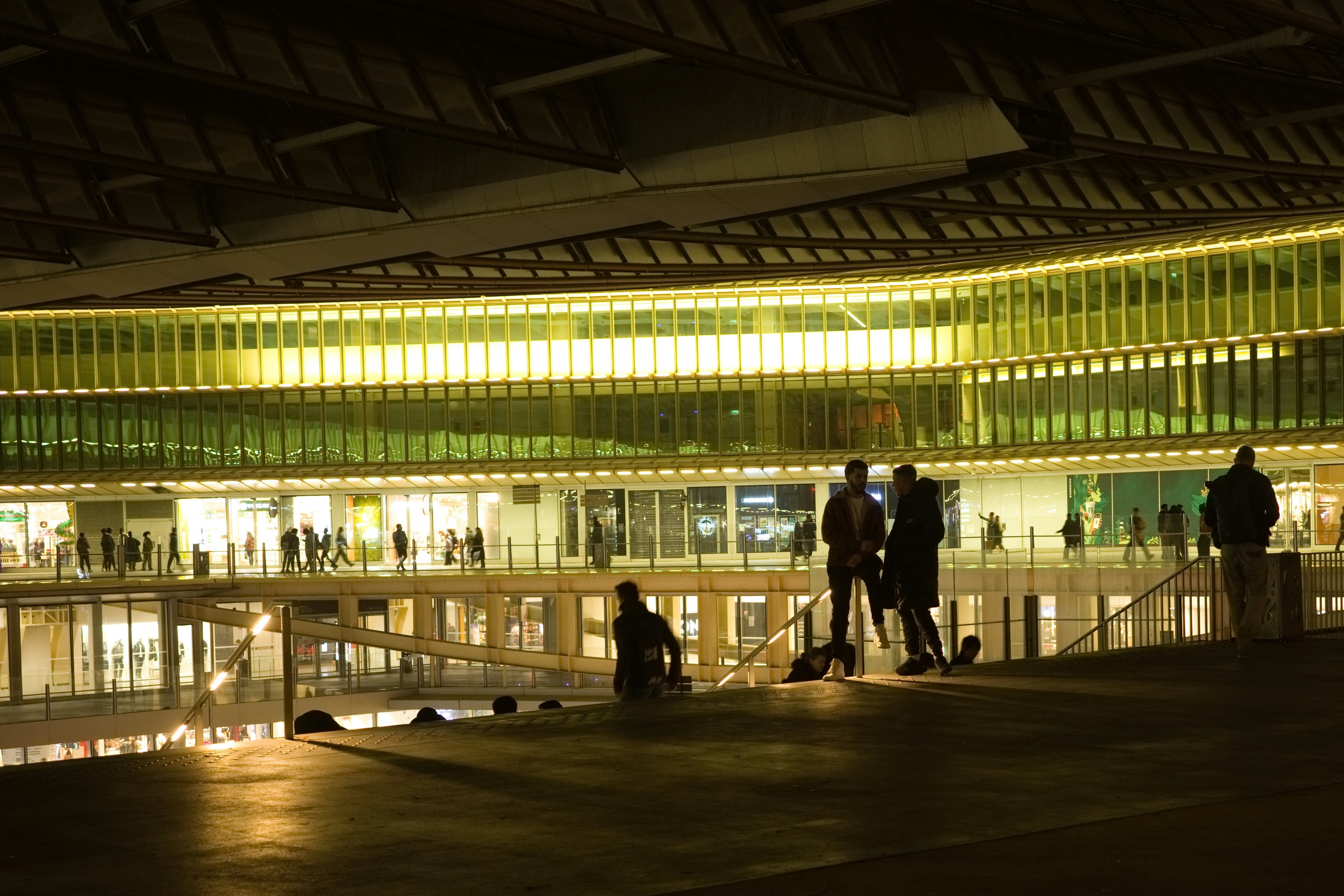 Intérieur d'un bâtiment moderne éclairé la nuit avec des silhouettes de personnes