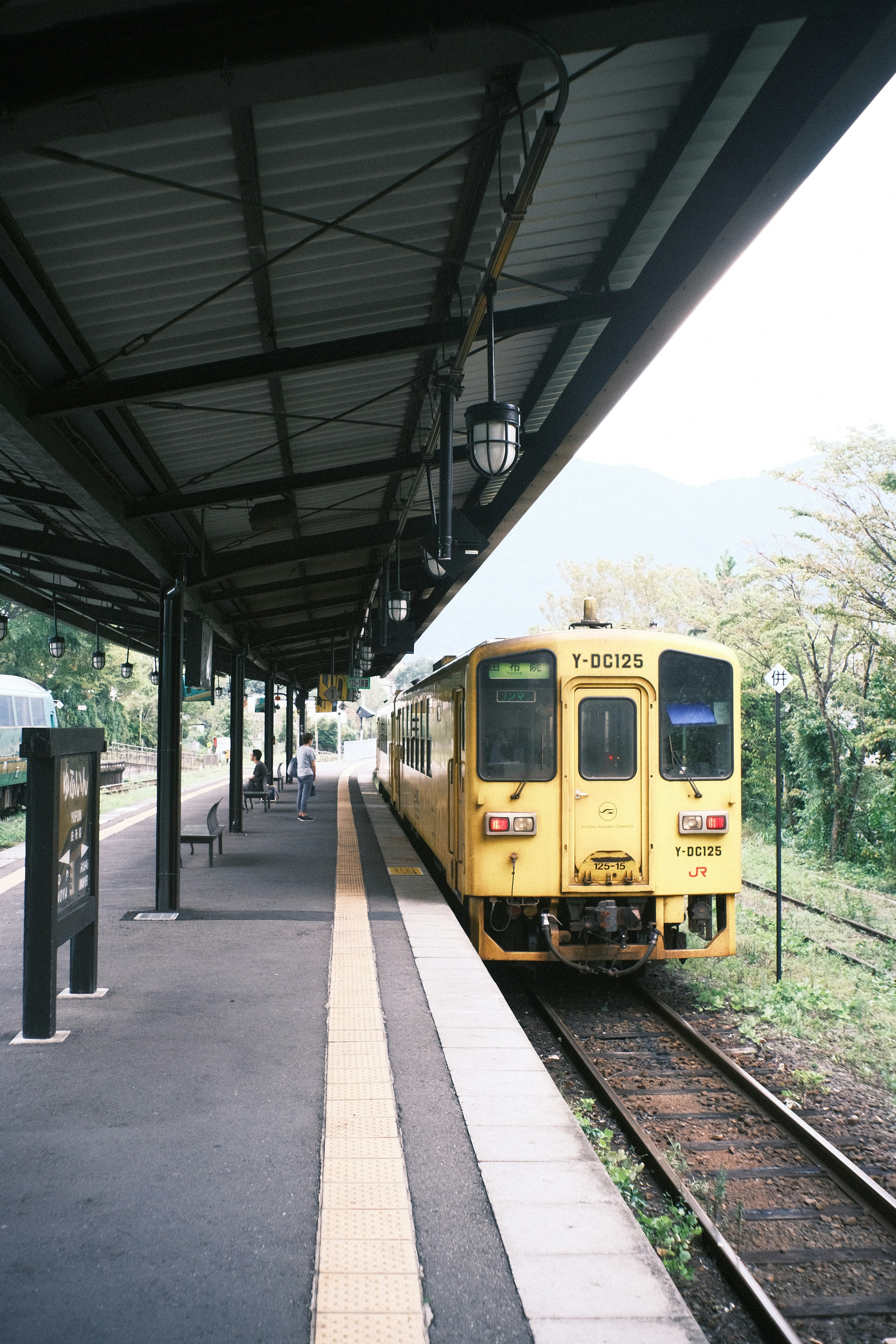 黄色い列車が停まっている駅のプラットフォームの風景