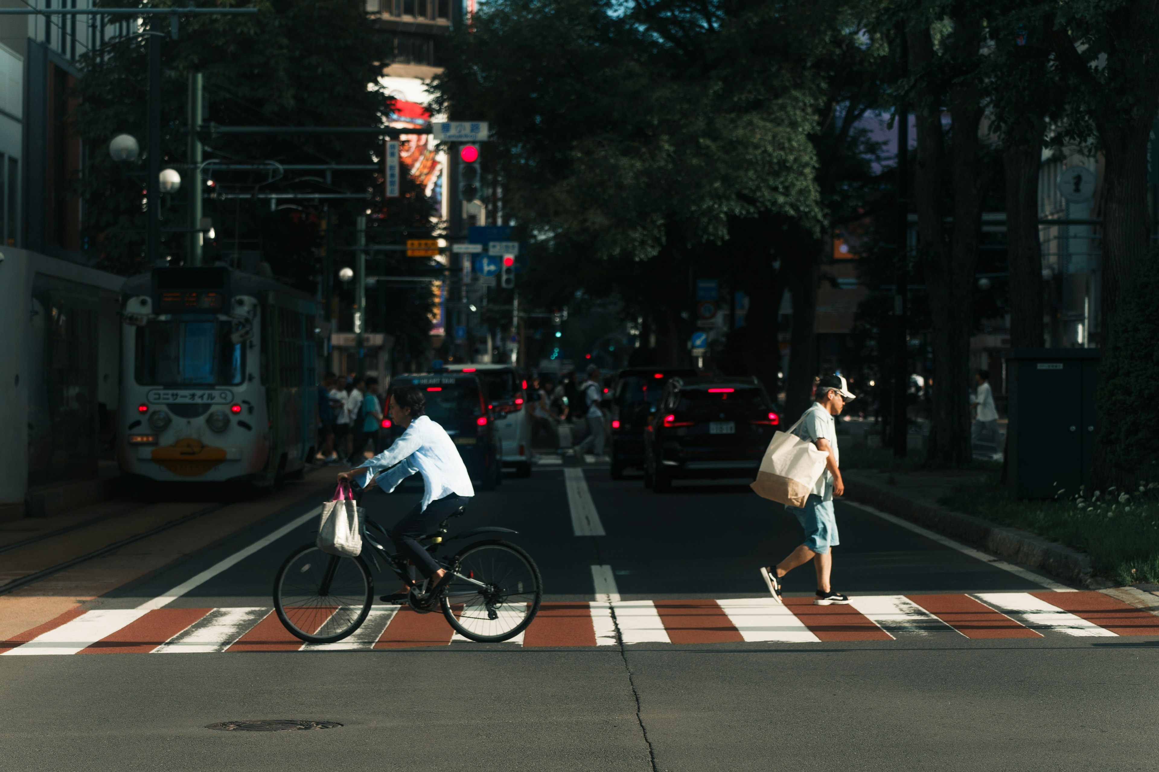 Eine Szene mit einem Mann auf einem Fahrrad und einem Fußgänger, der die Straße überquert städtische Umgebung mit sichtbaren Verkehrsampeln