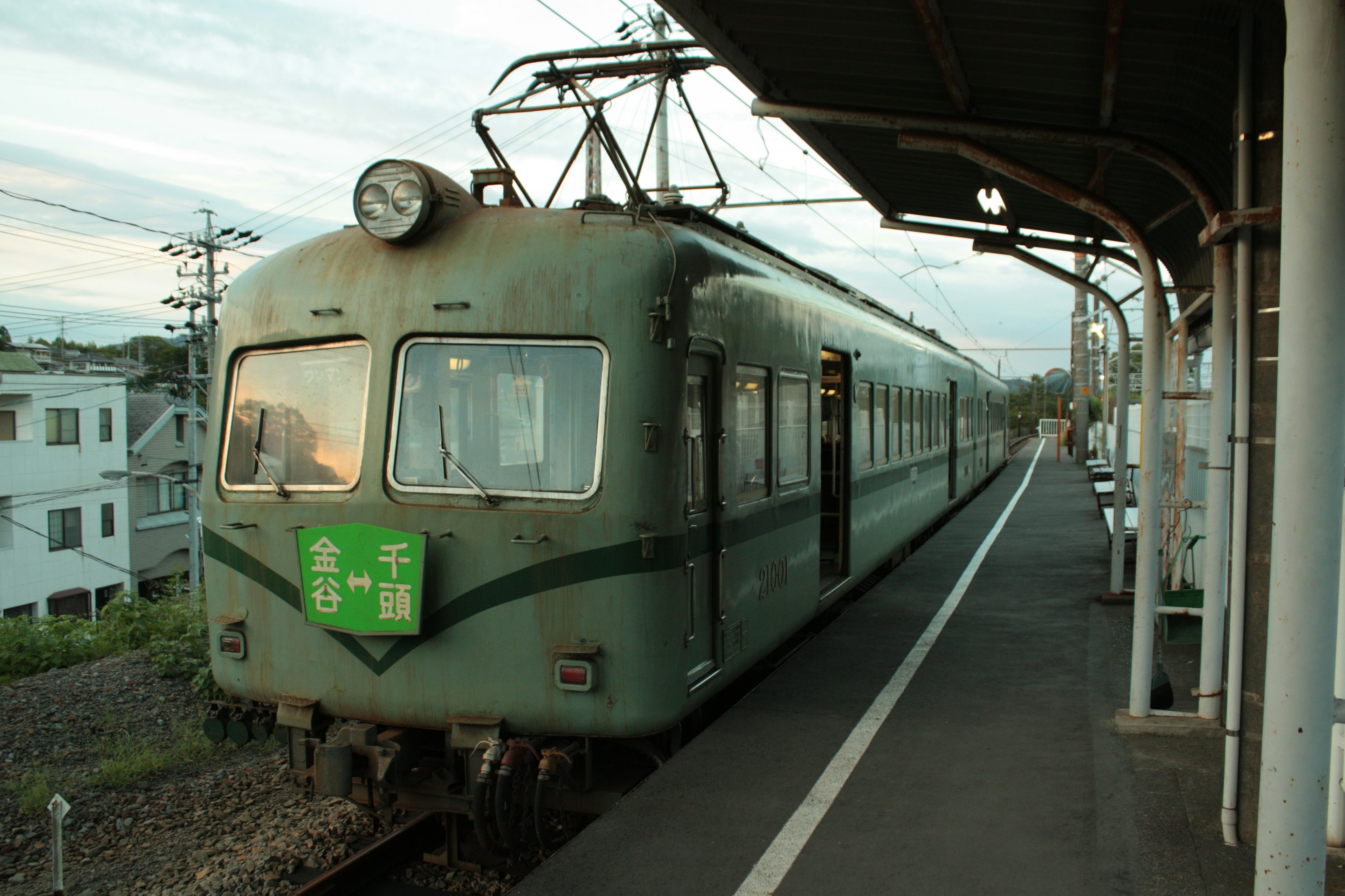 緑色の電車が駅のホームに停車している風景