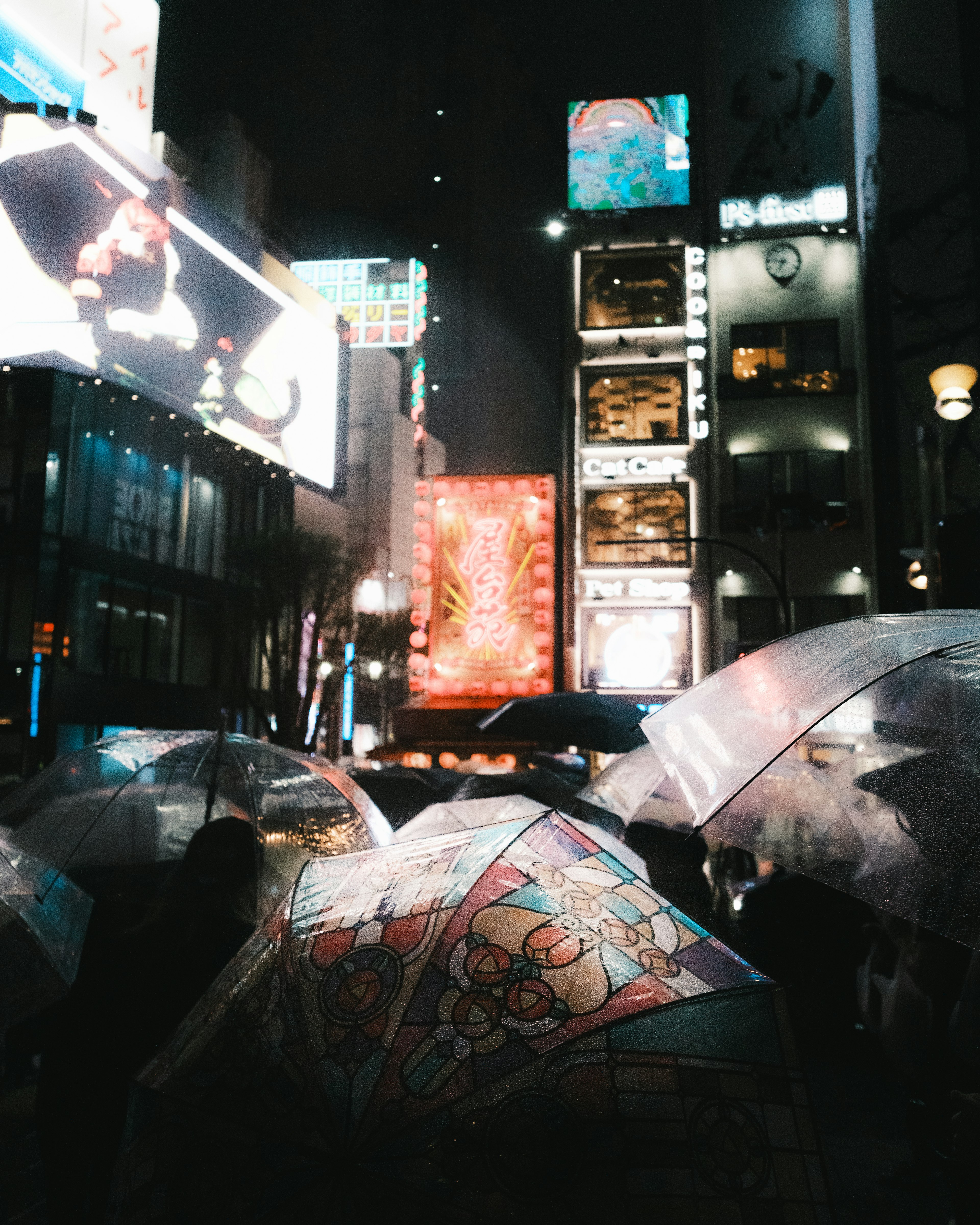 Foule de parapluies sous des lumières néon dans une rue animée