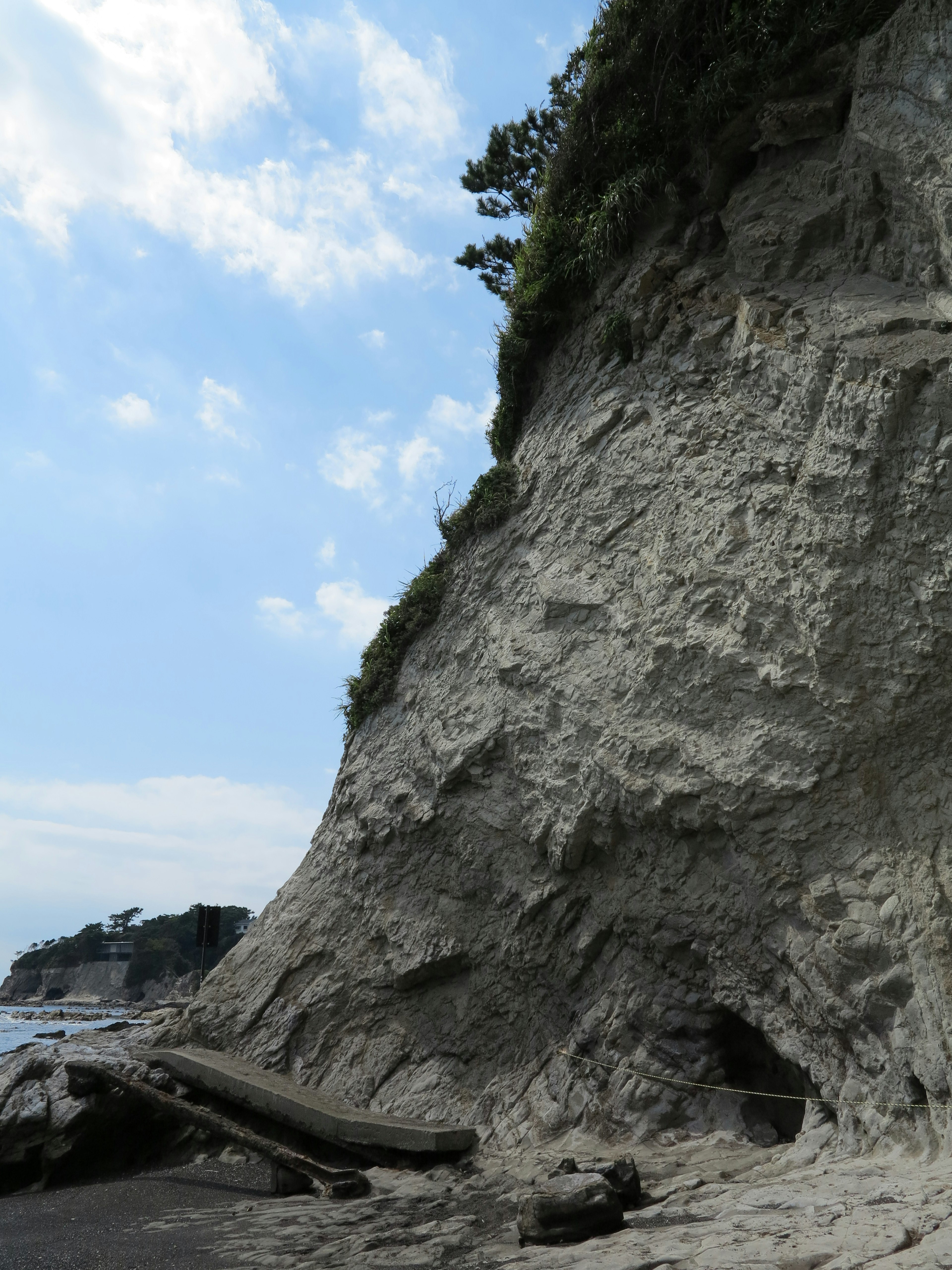 Falesia sulla spiaggia con texture rocciosa e passerella in legno cielo blu e nuvole