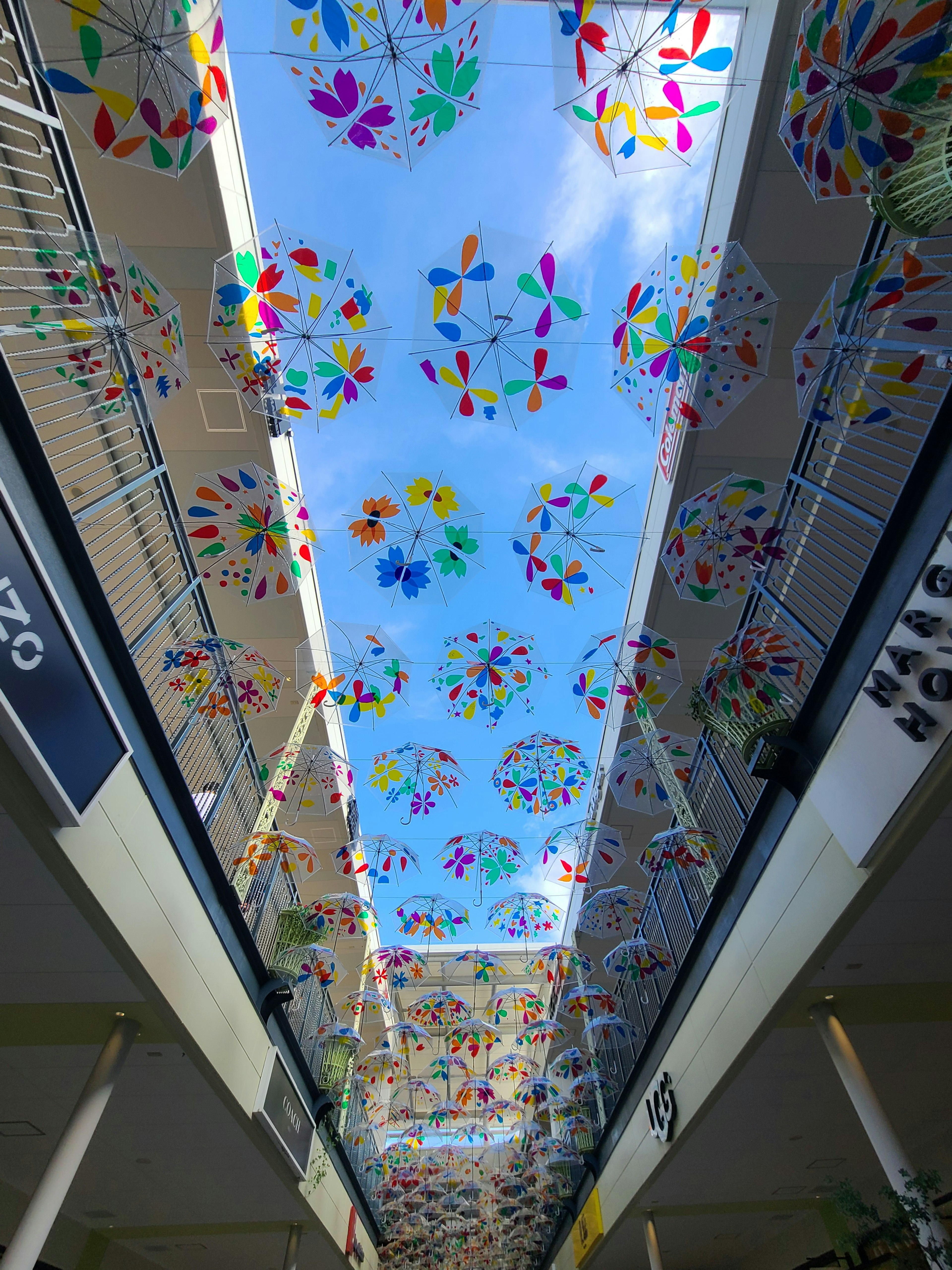 Indoor walkway adorned with colorful umbrellas under a blue sky