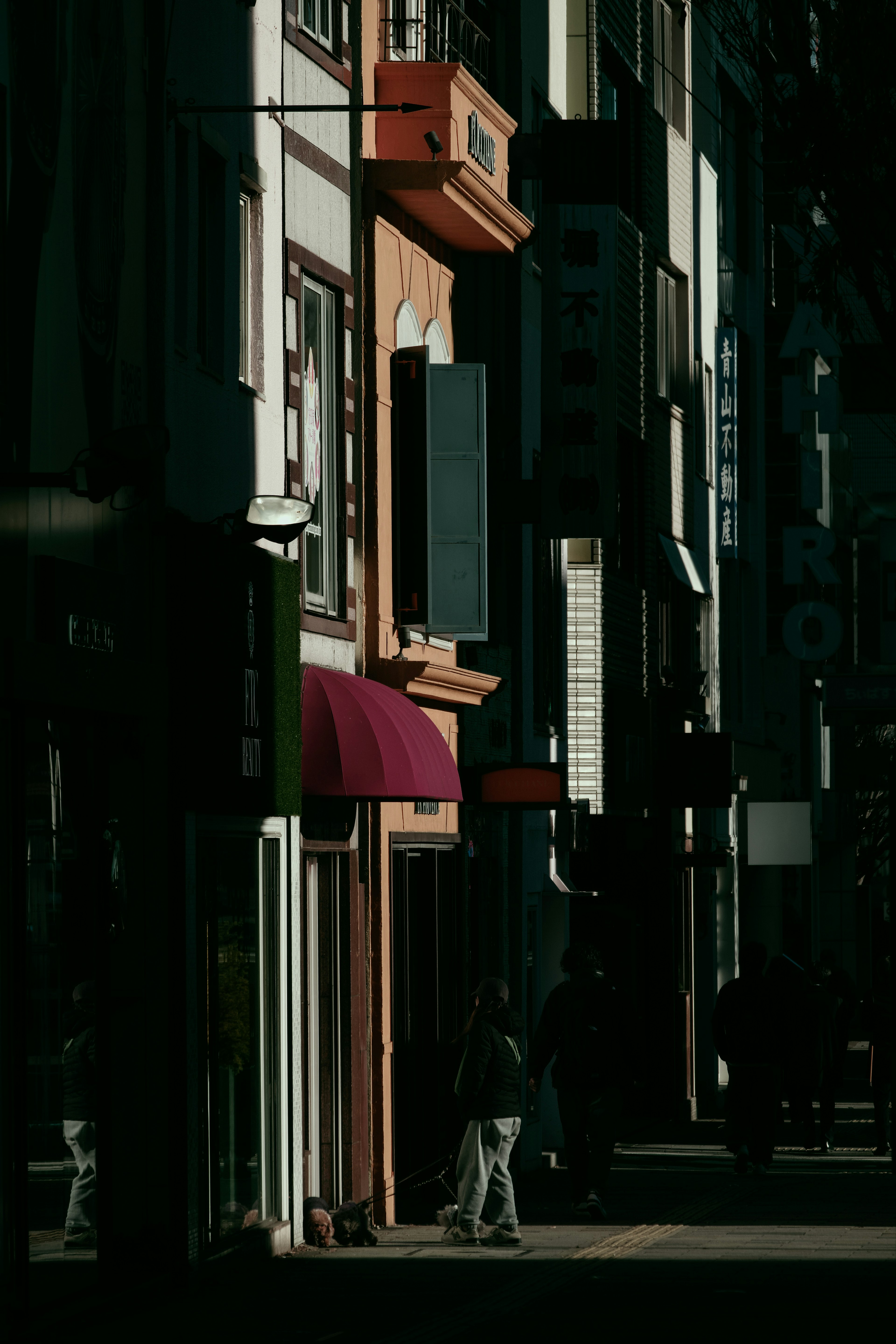 Frentes de tiendas a lo largo de una calle oscura con un toldo rojo