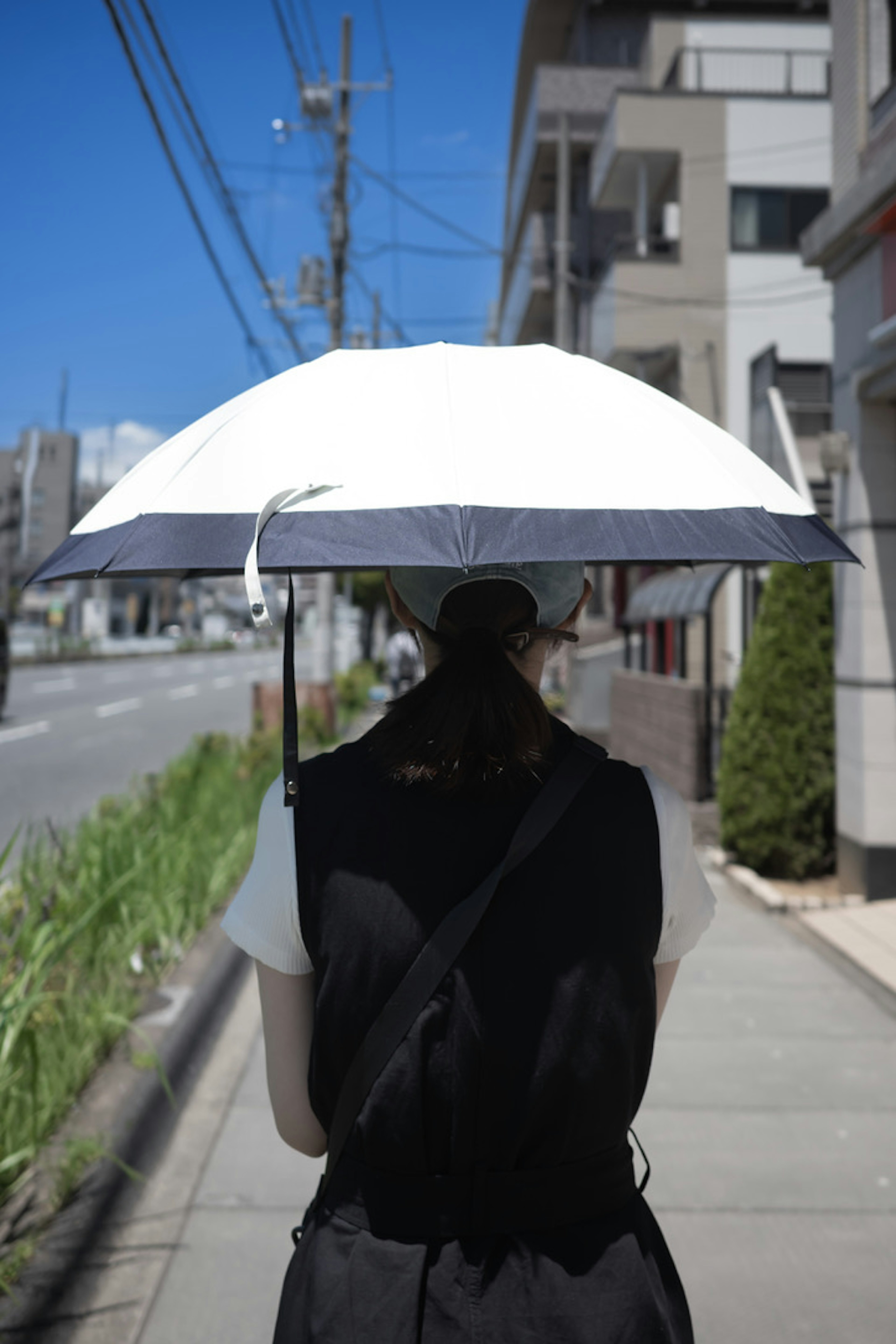 A woman walking with a sun umbrella on a city street