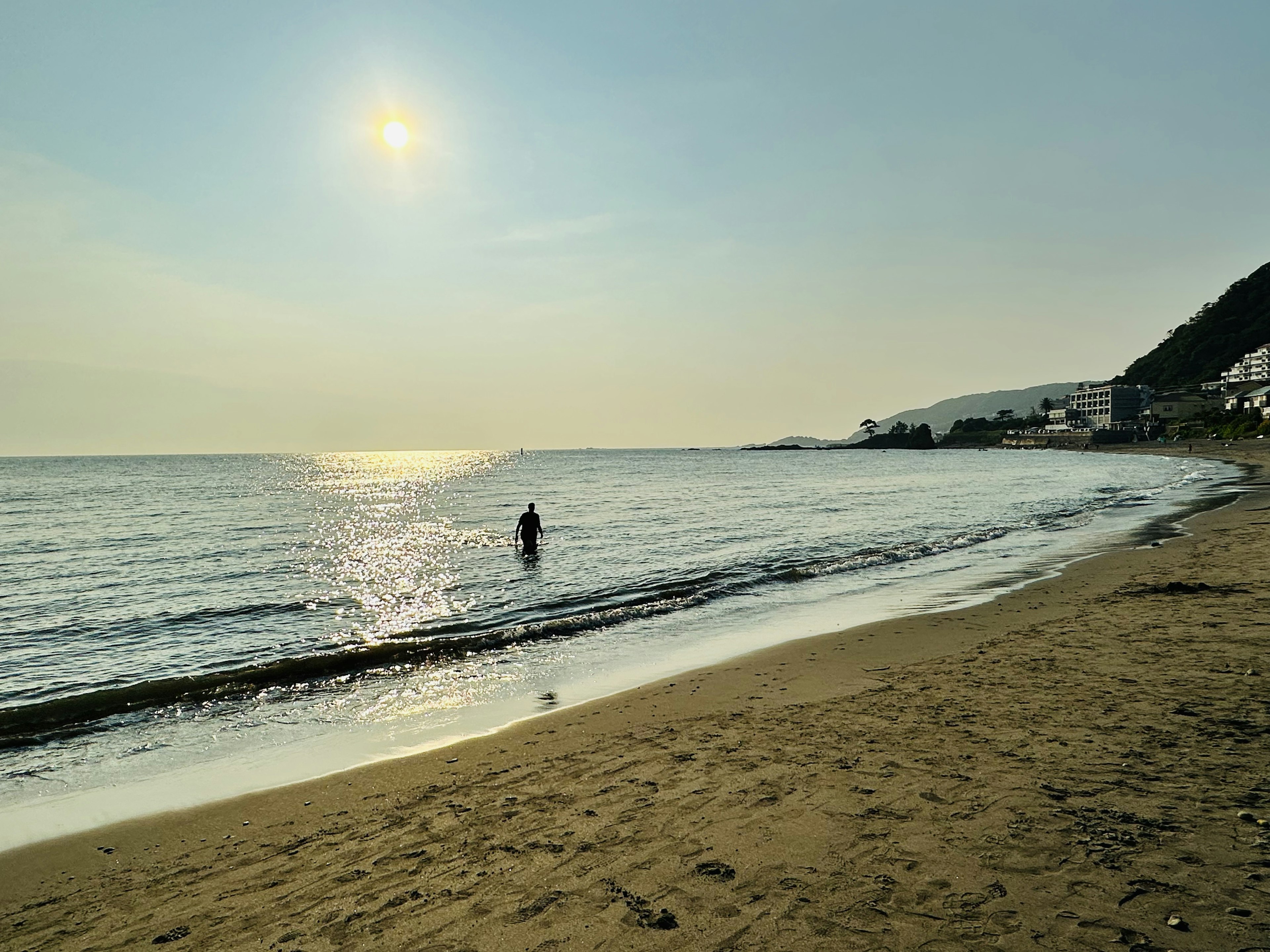 Una persona che cammina sulla spiaggia sotto il sole