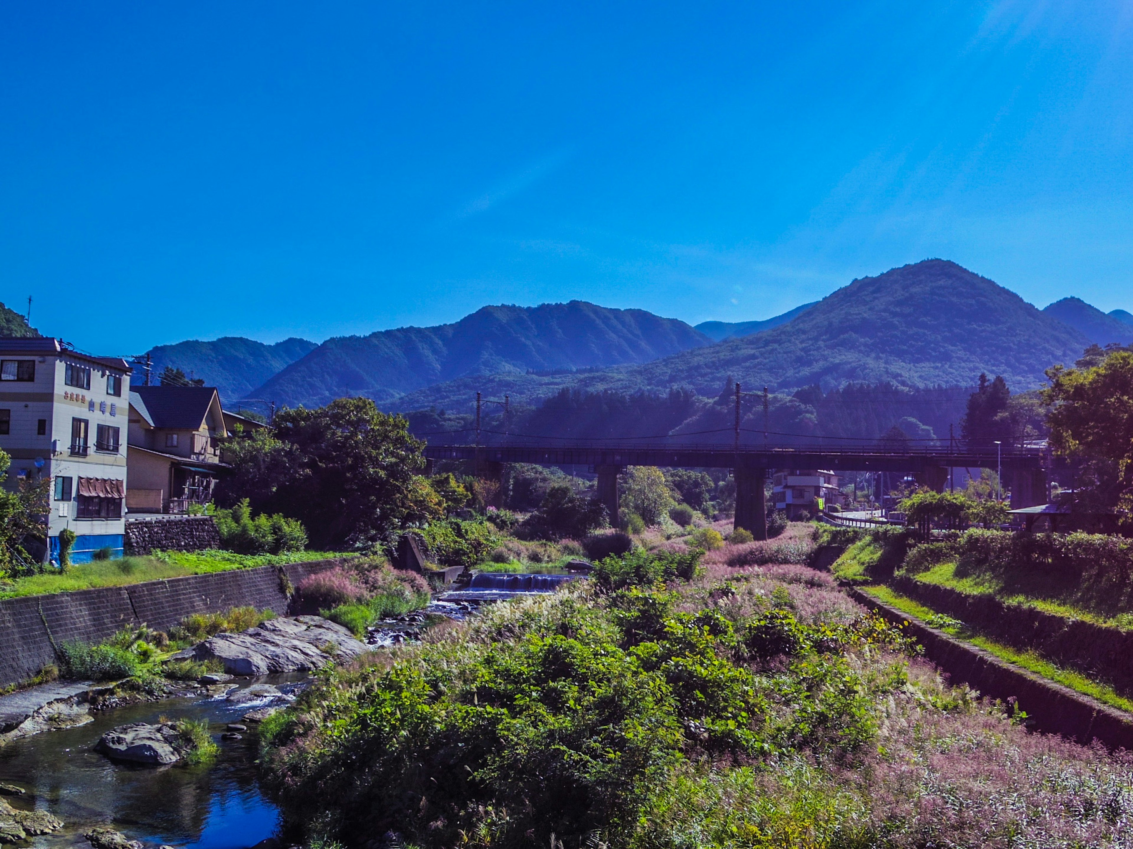 Vista panoramica di montagne e un fiume sotto un cielo blu chiaro con edifici antichi