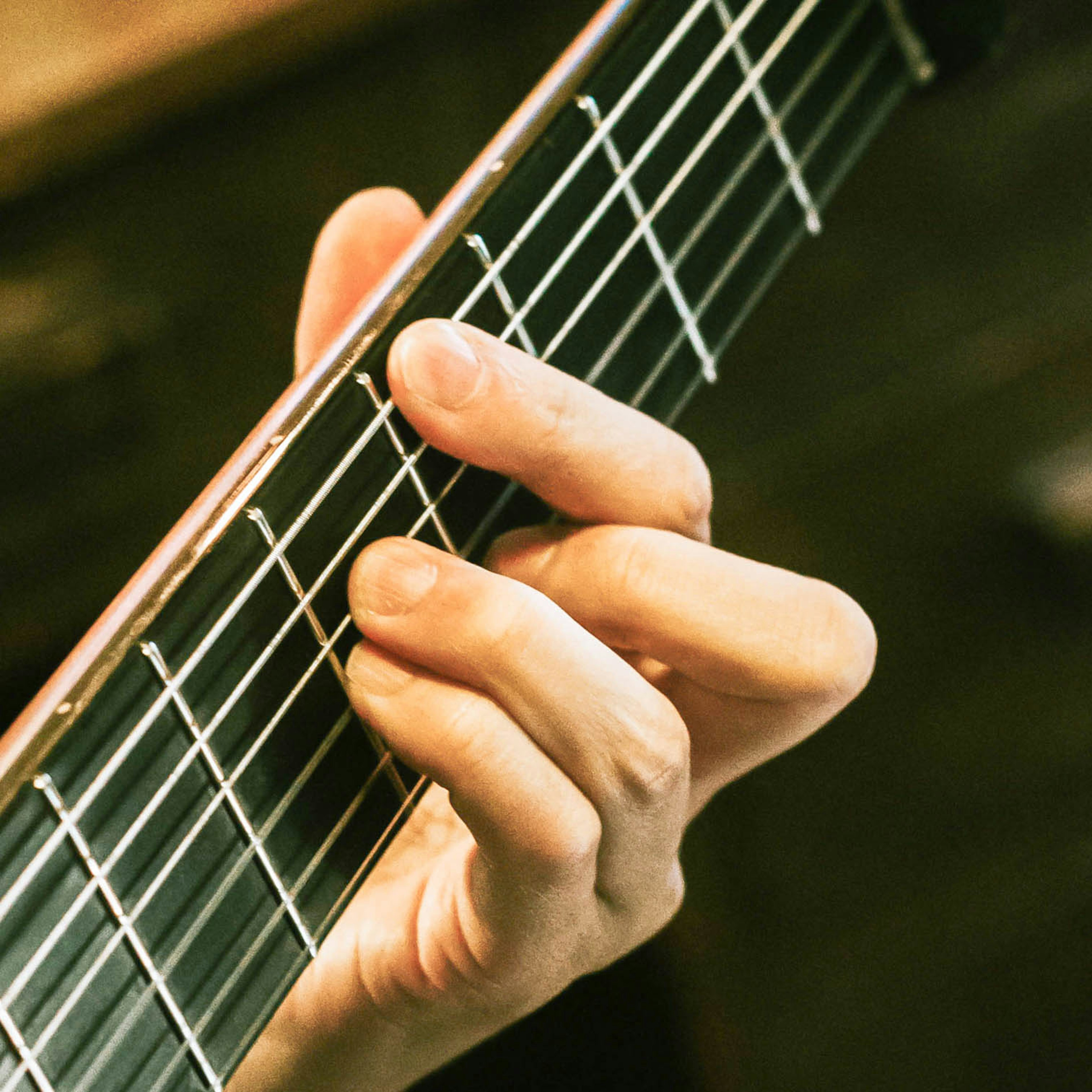 Nahaufnahme einer Hand, die Gitarrensaiten drückt