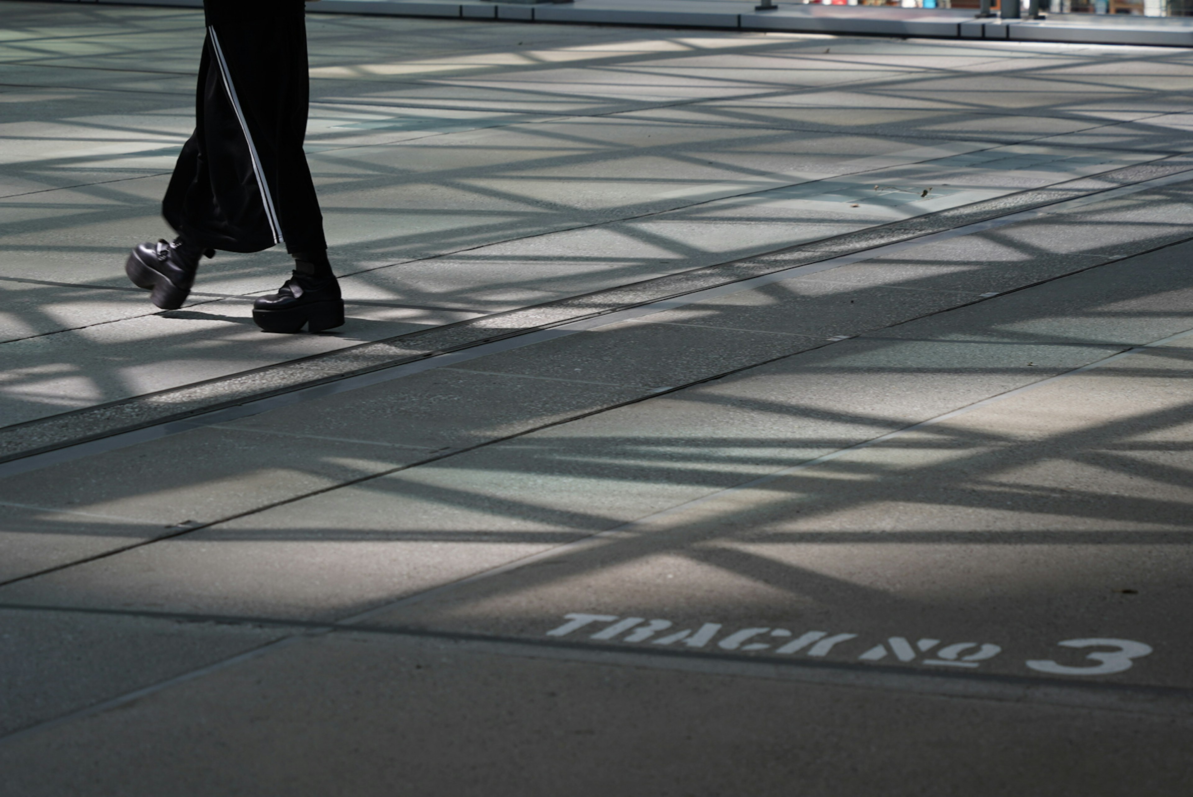 Eine Person, die auf einem Betonboden geht, mit Schatten und dem Text Tracking Nr 3