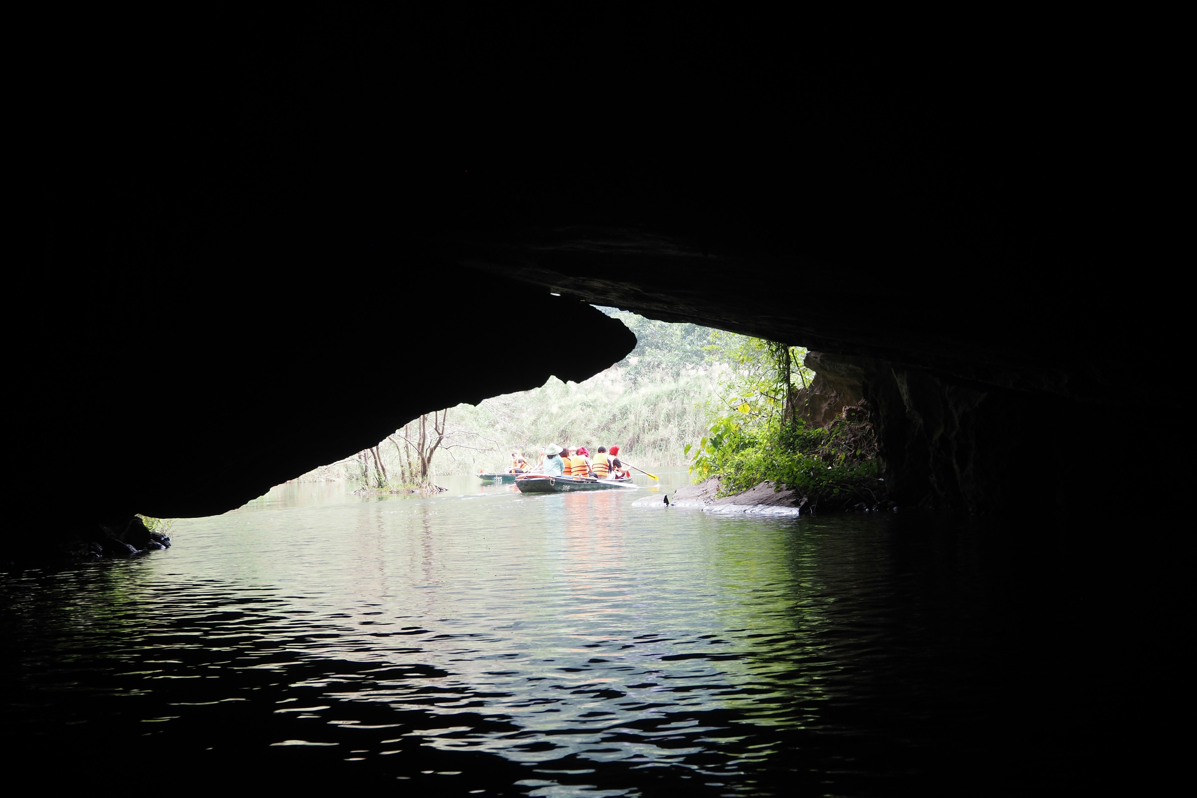 View of a serene water surface and boat from a dark cave