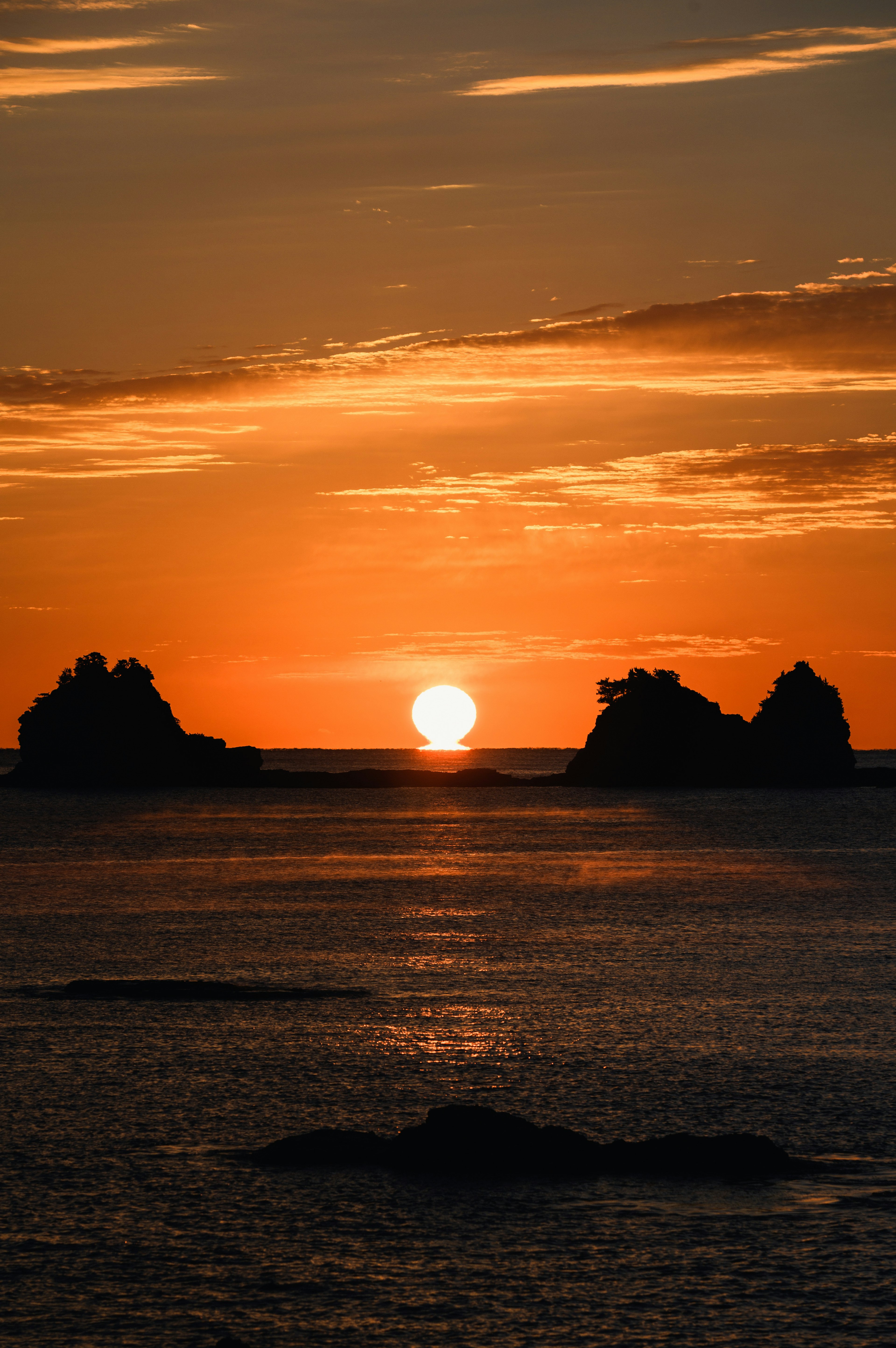 Schöner Sonnenuntergang über dem Ozean mit silhouettierten Felsen