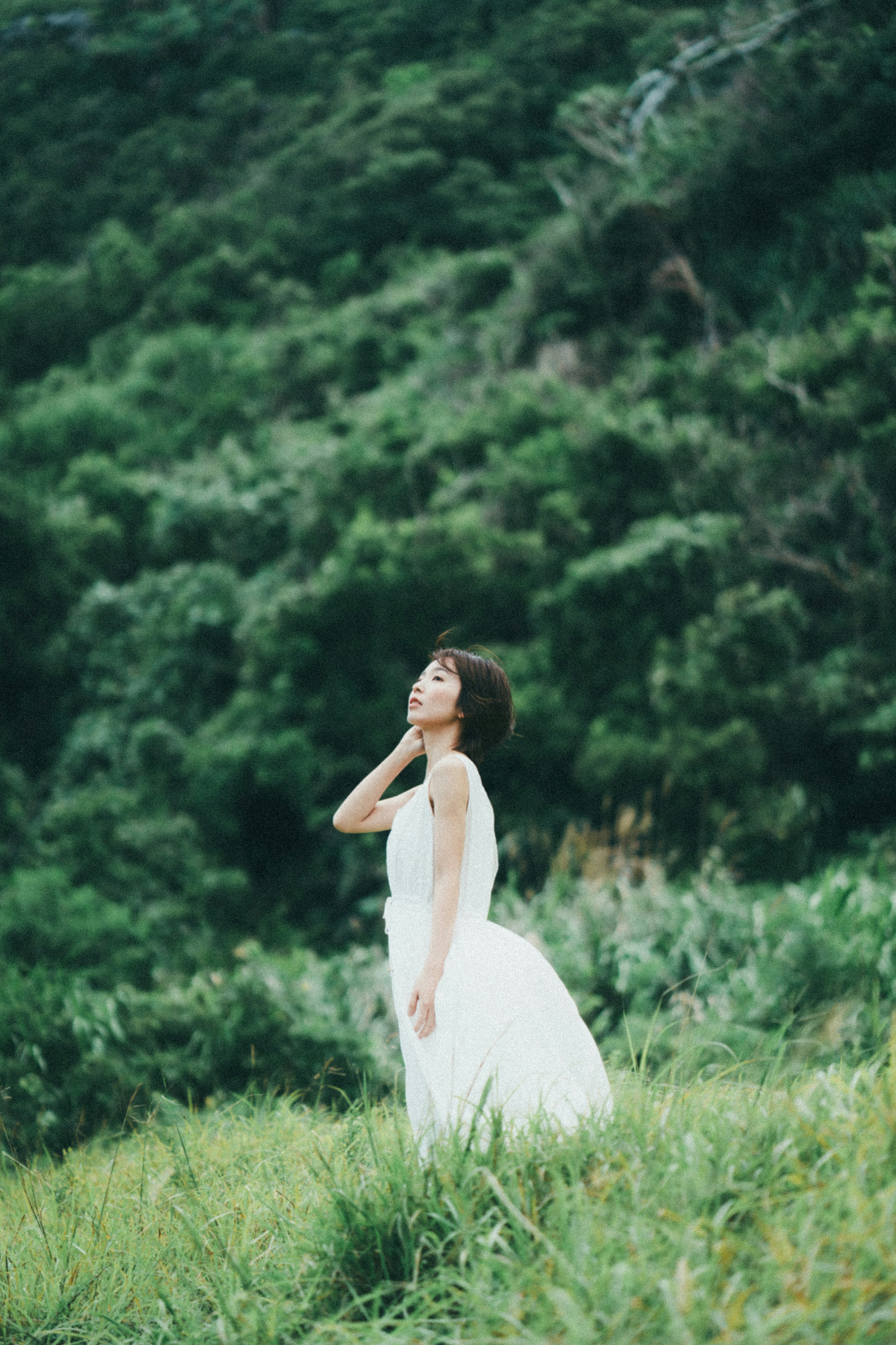 A woman in a white dress posing amidst lush green nature