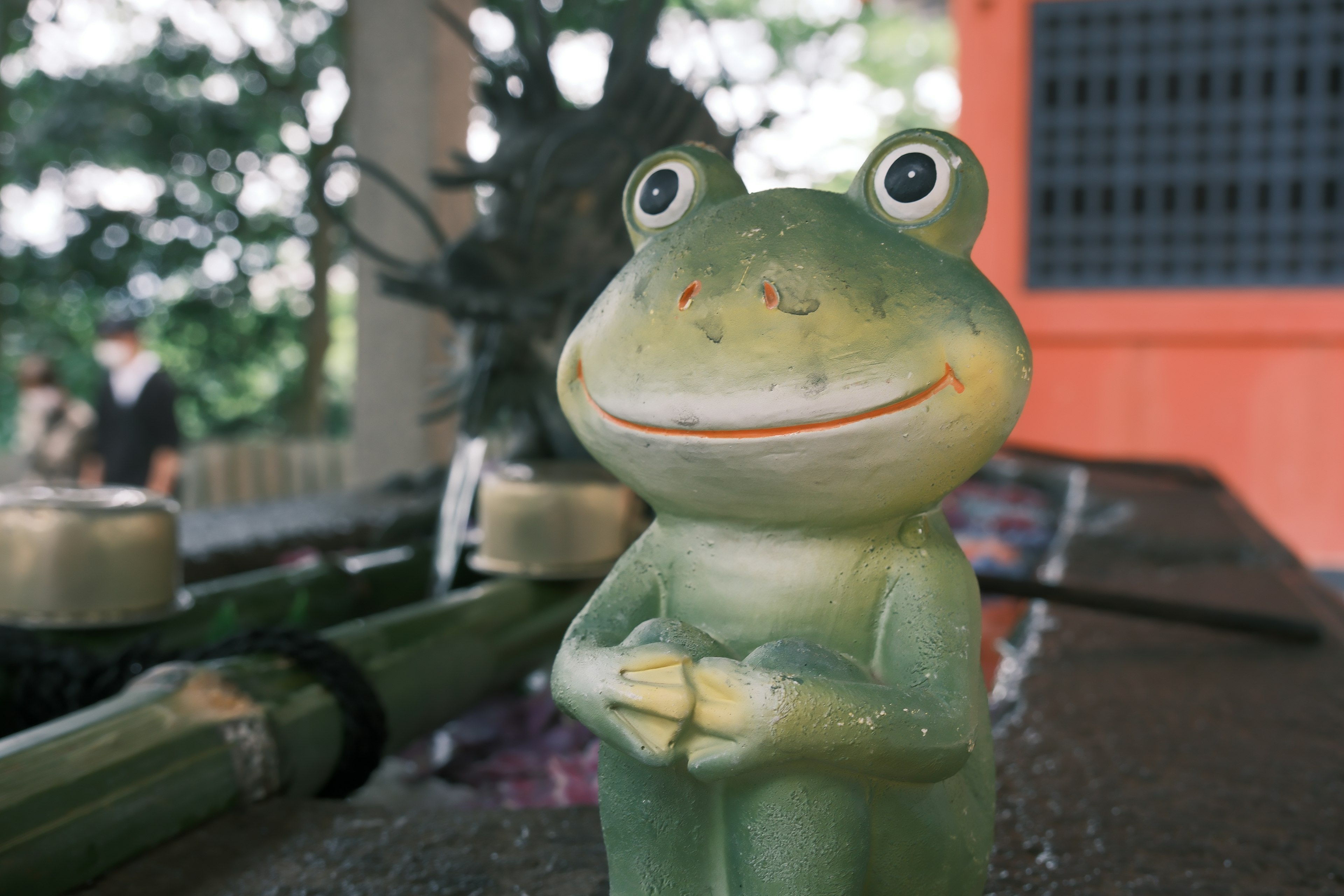 A smiling green frog figurine with a cheerful expression