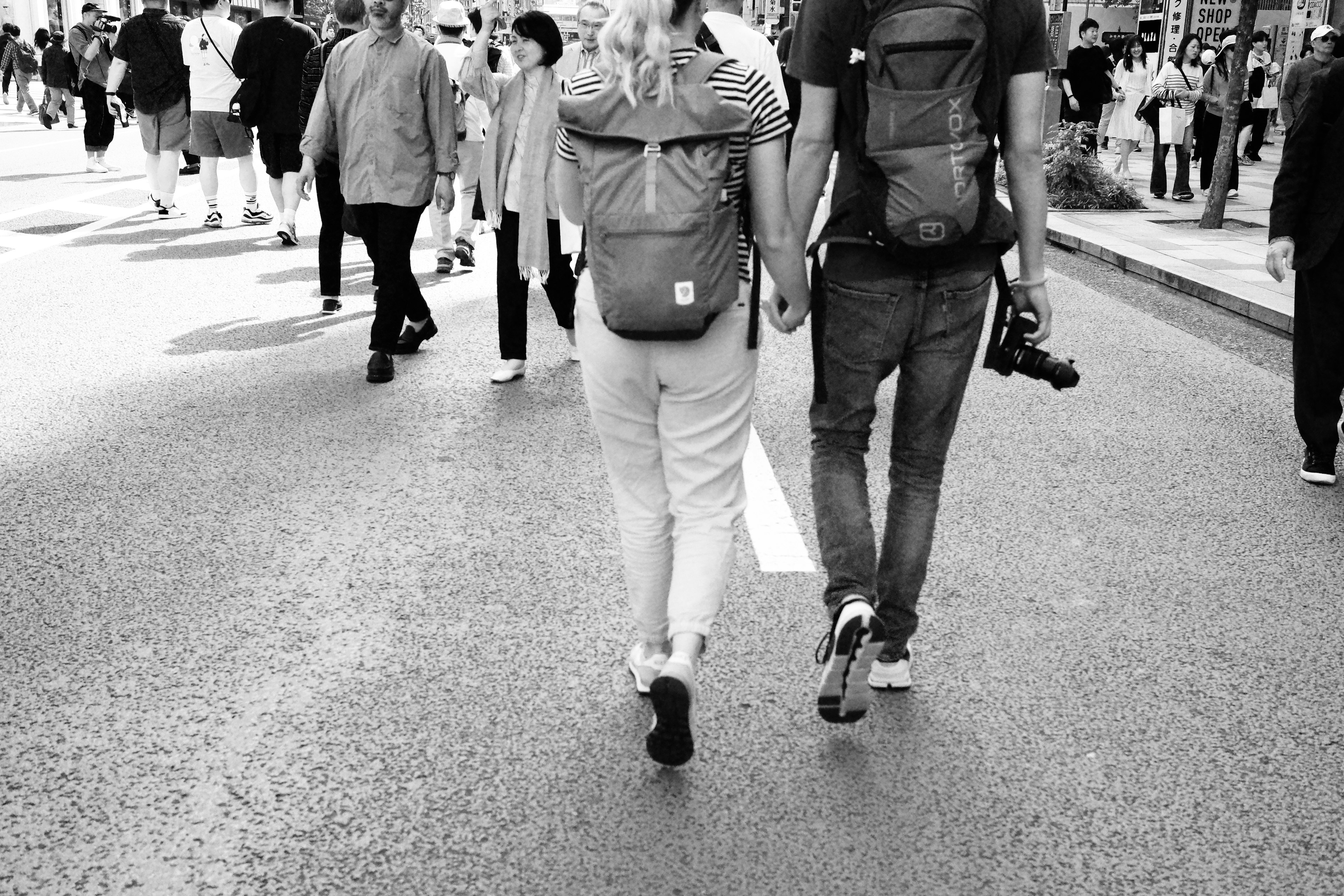 Couple walking in black and white city street from behind