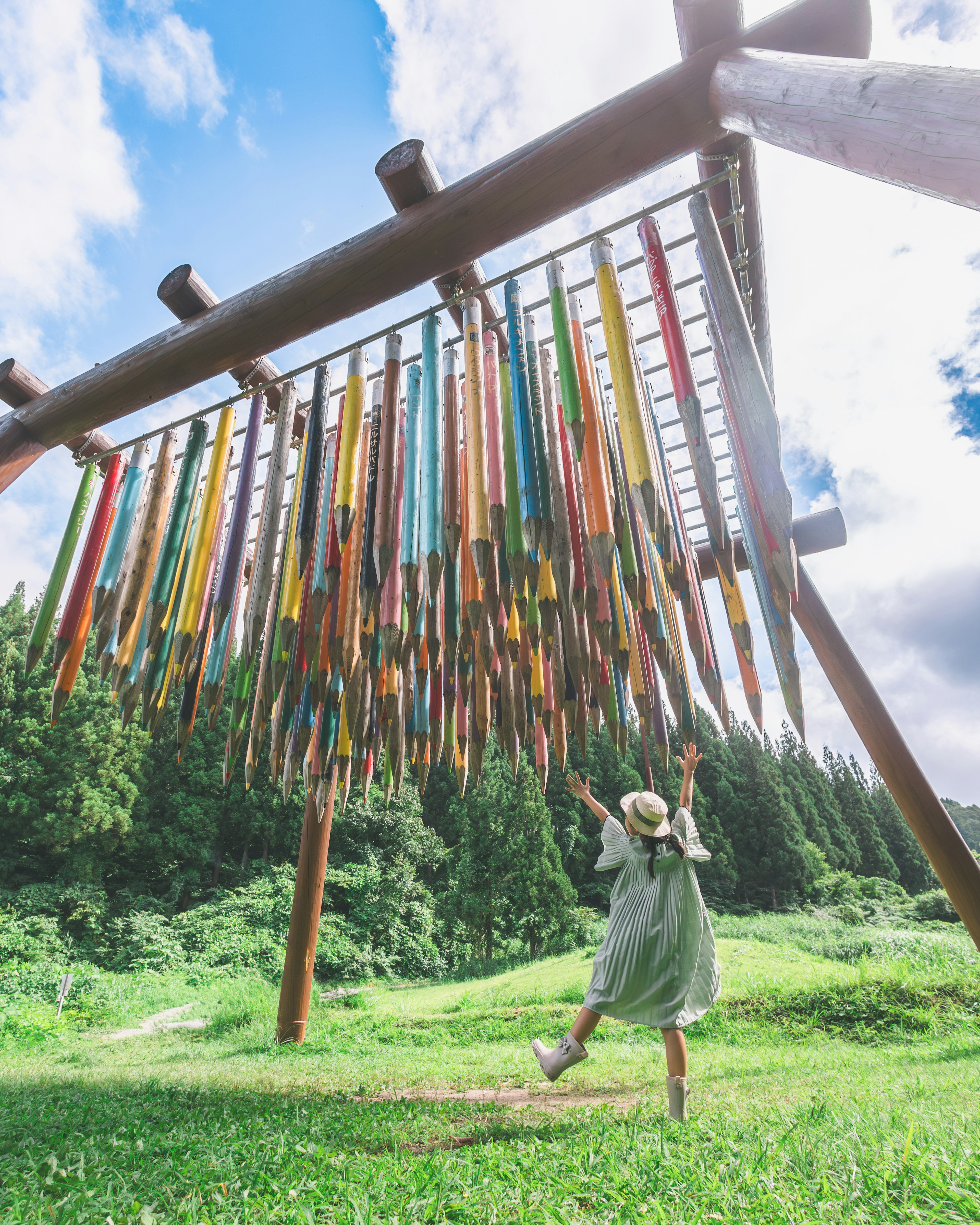 Una mujer disfrutando de una instalación artística de lápices coloridos en un paisaje verde