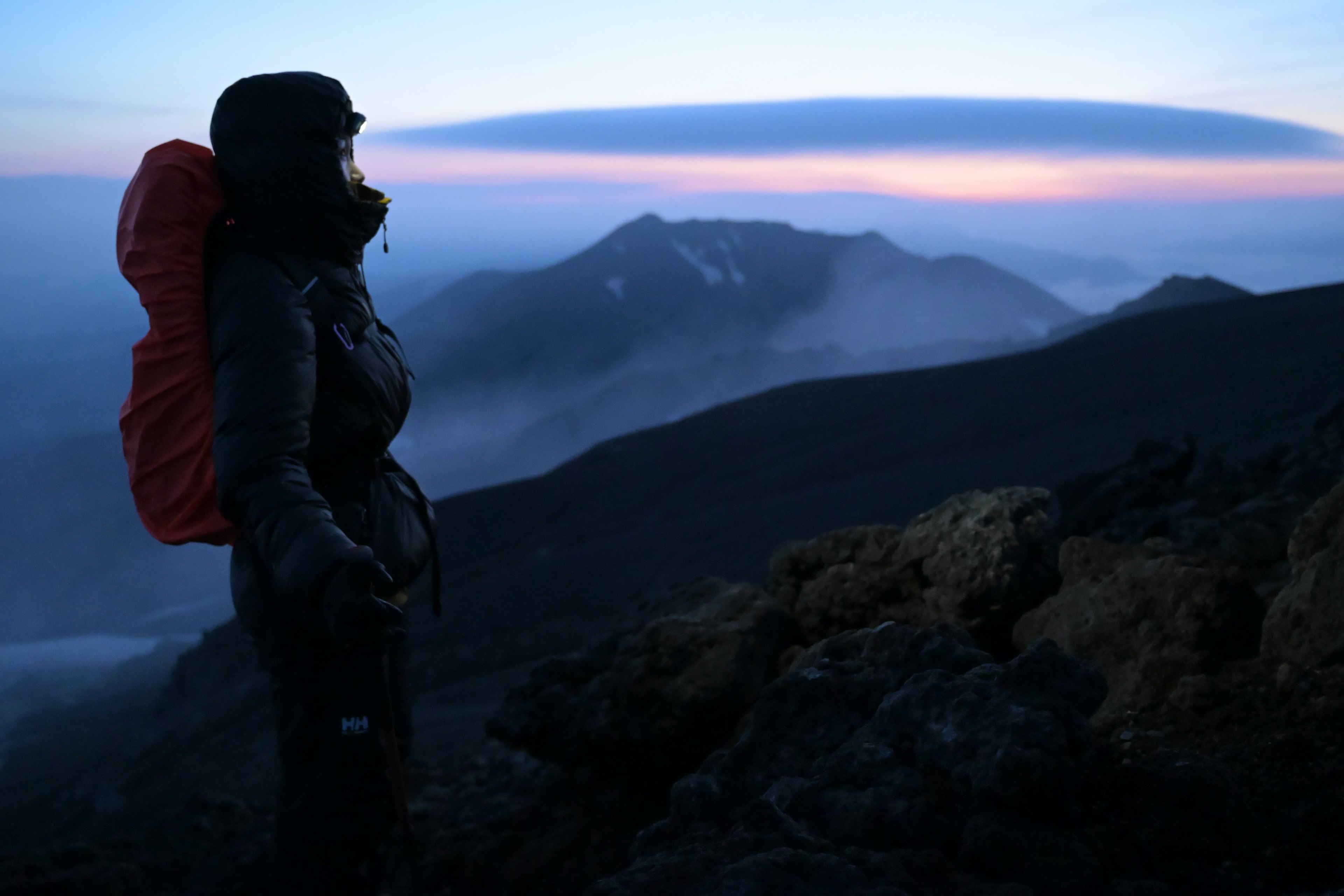 夕焼けの山を見つめる登山者のシルエット