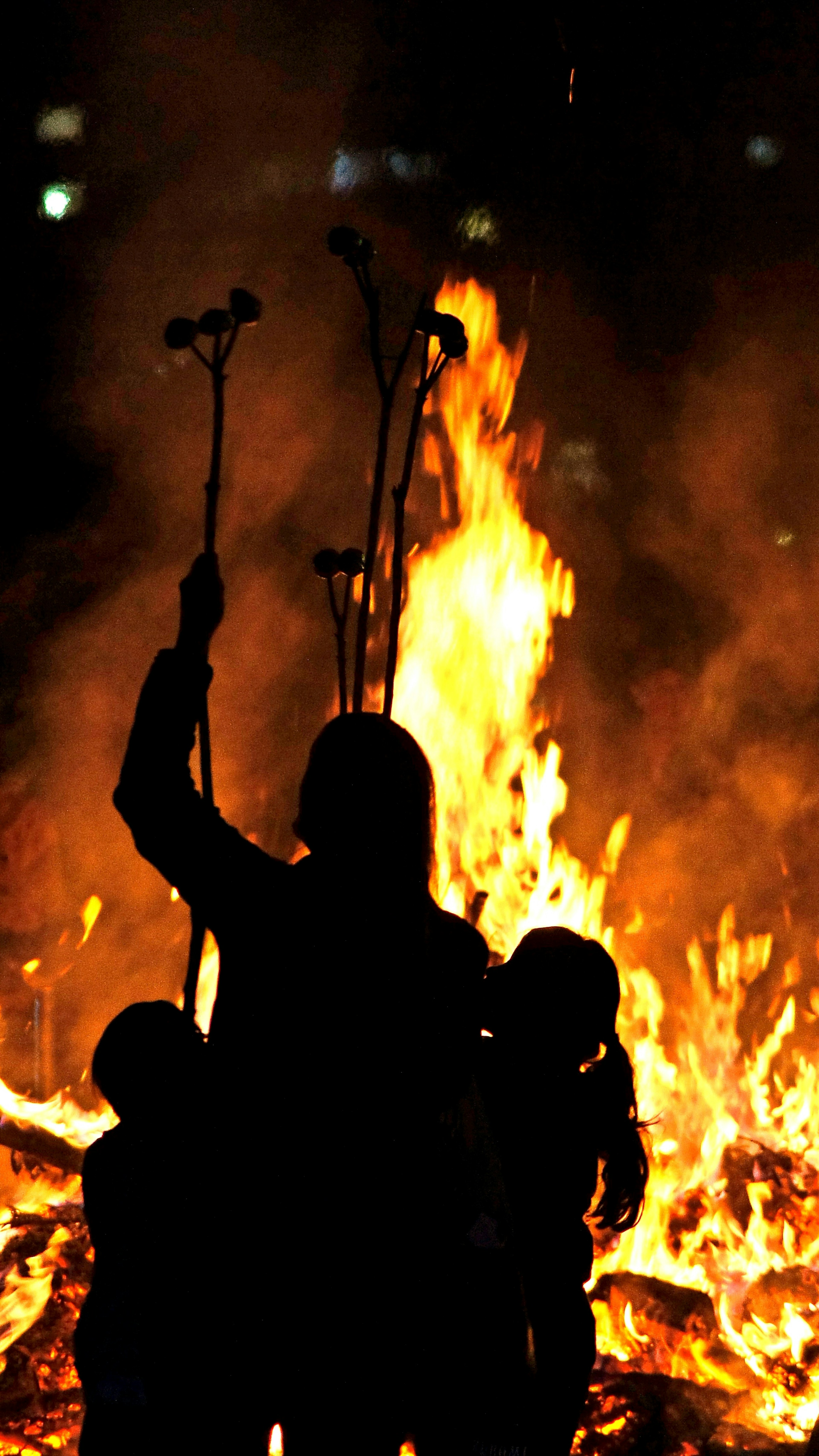 Silhouette di persone in piedi davanti a un fuoco luminoso