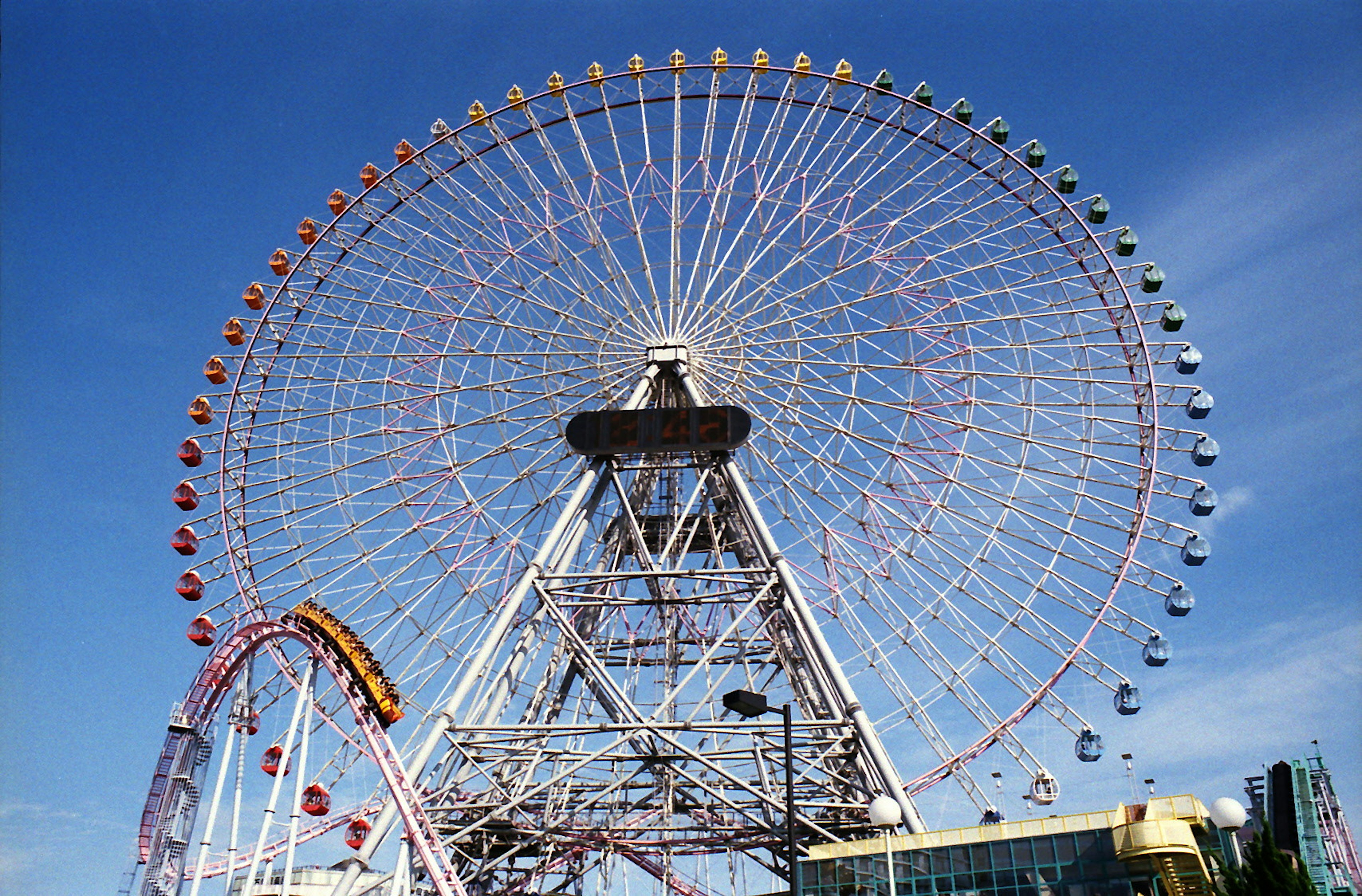 Roda Ferris berwarna-warni di bawah langit biru cerah