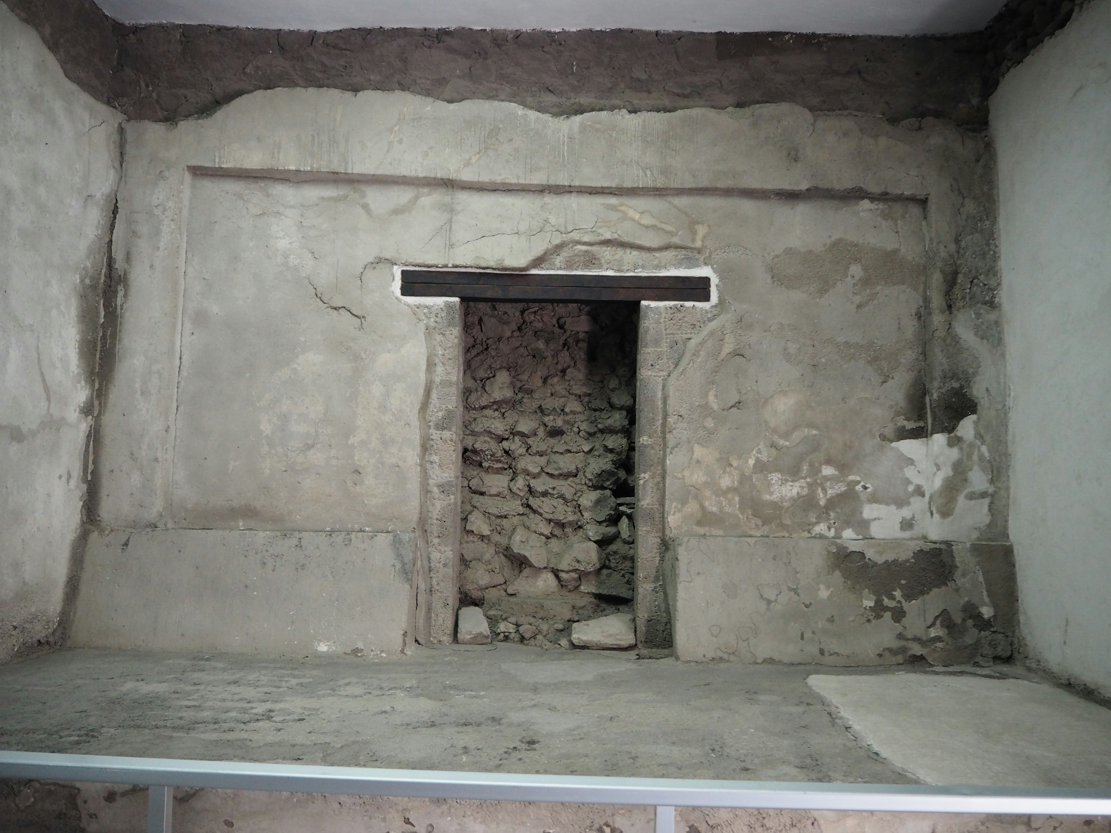 Interior de una habitación antigua con puerta de piedra y paredes texturizadas