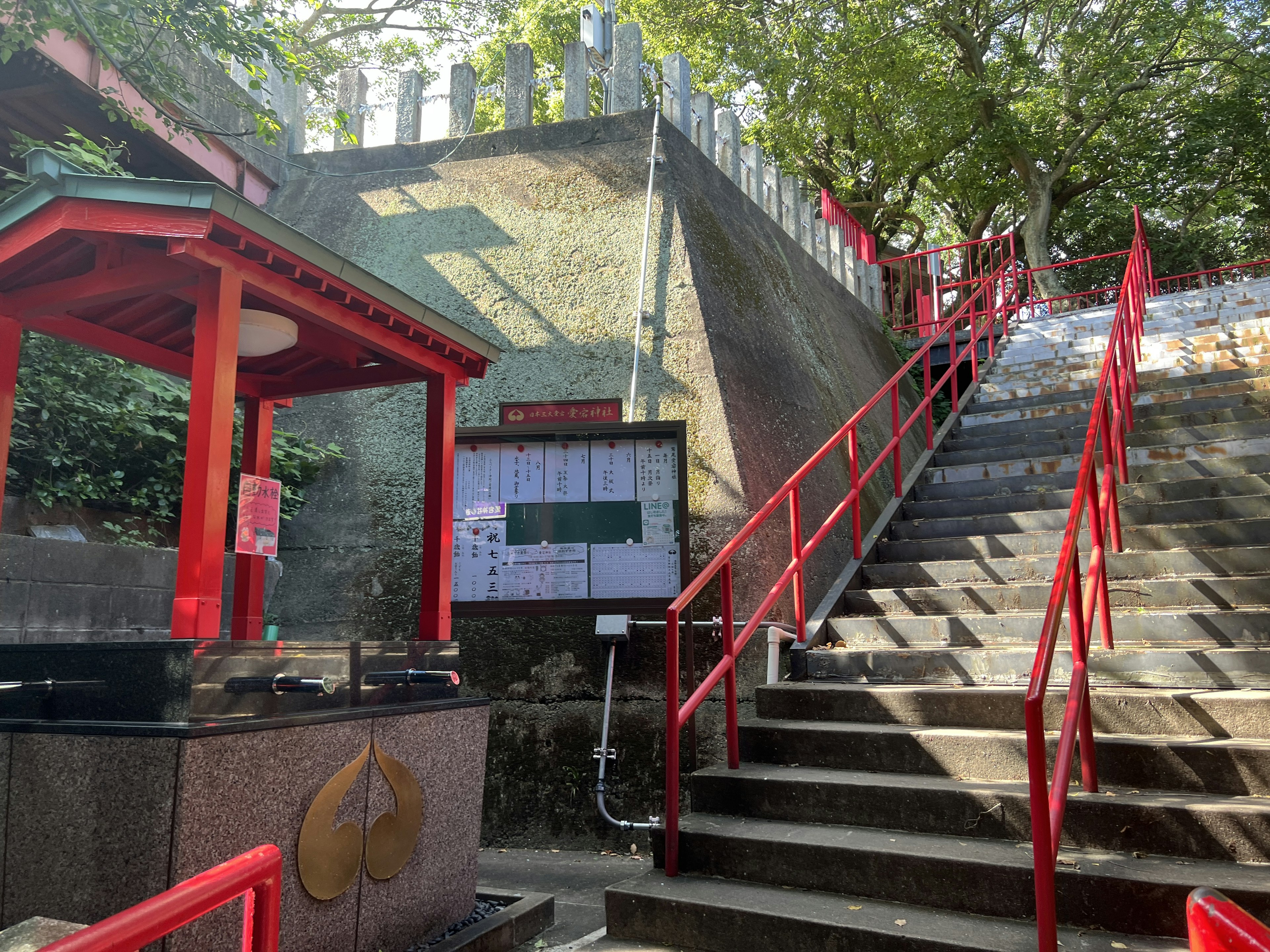 赤い手すりの階段と神社の建物がある風景