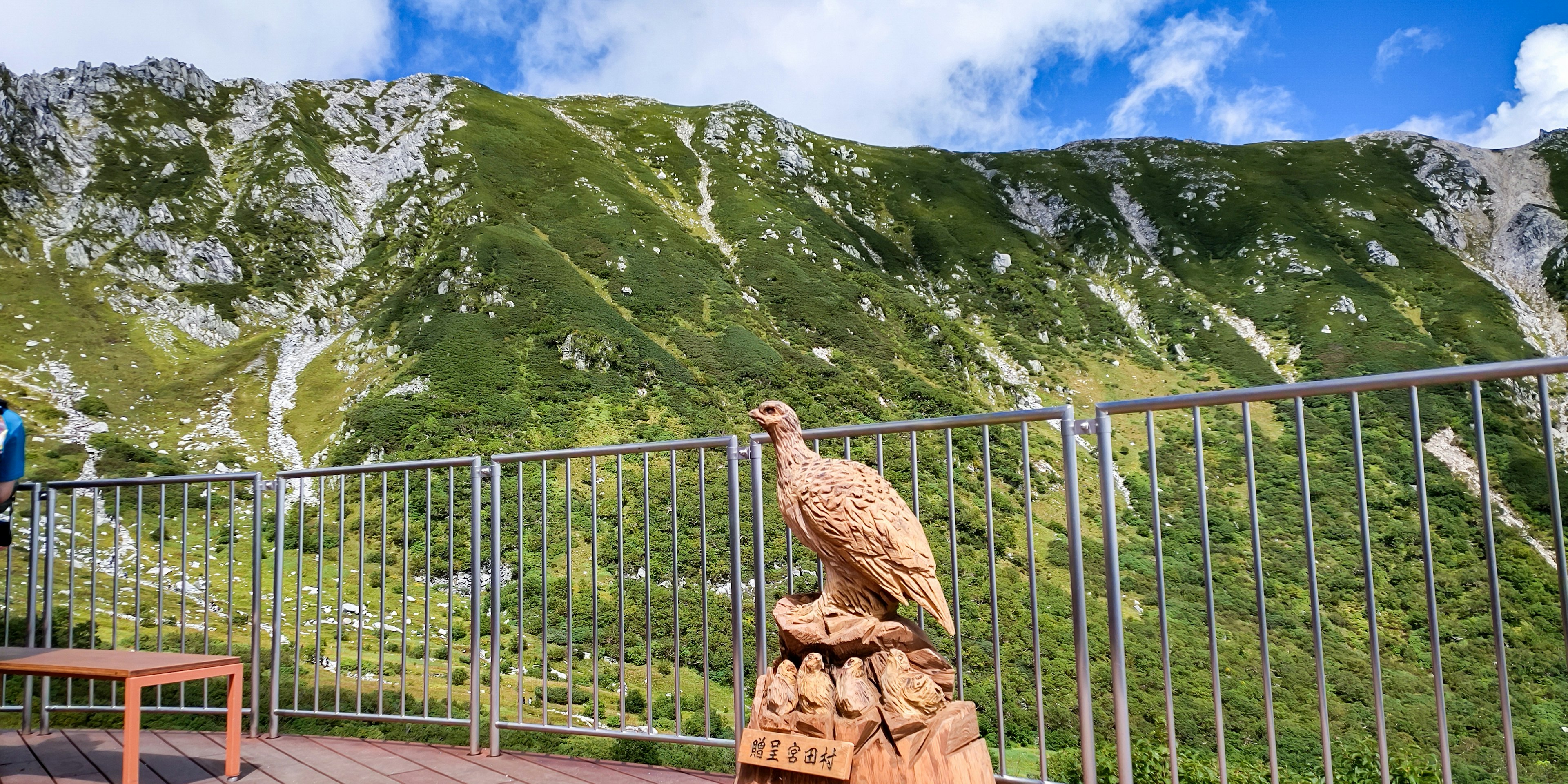 山の景色を背景にした鷲の彫刻と木製のベンチ