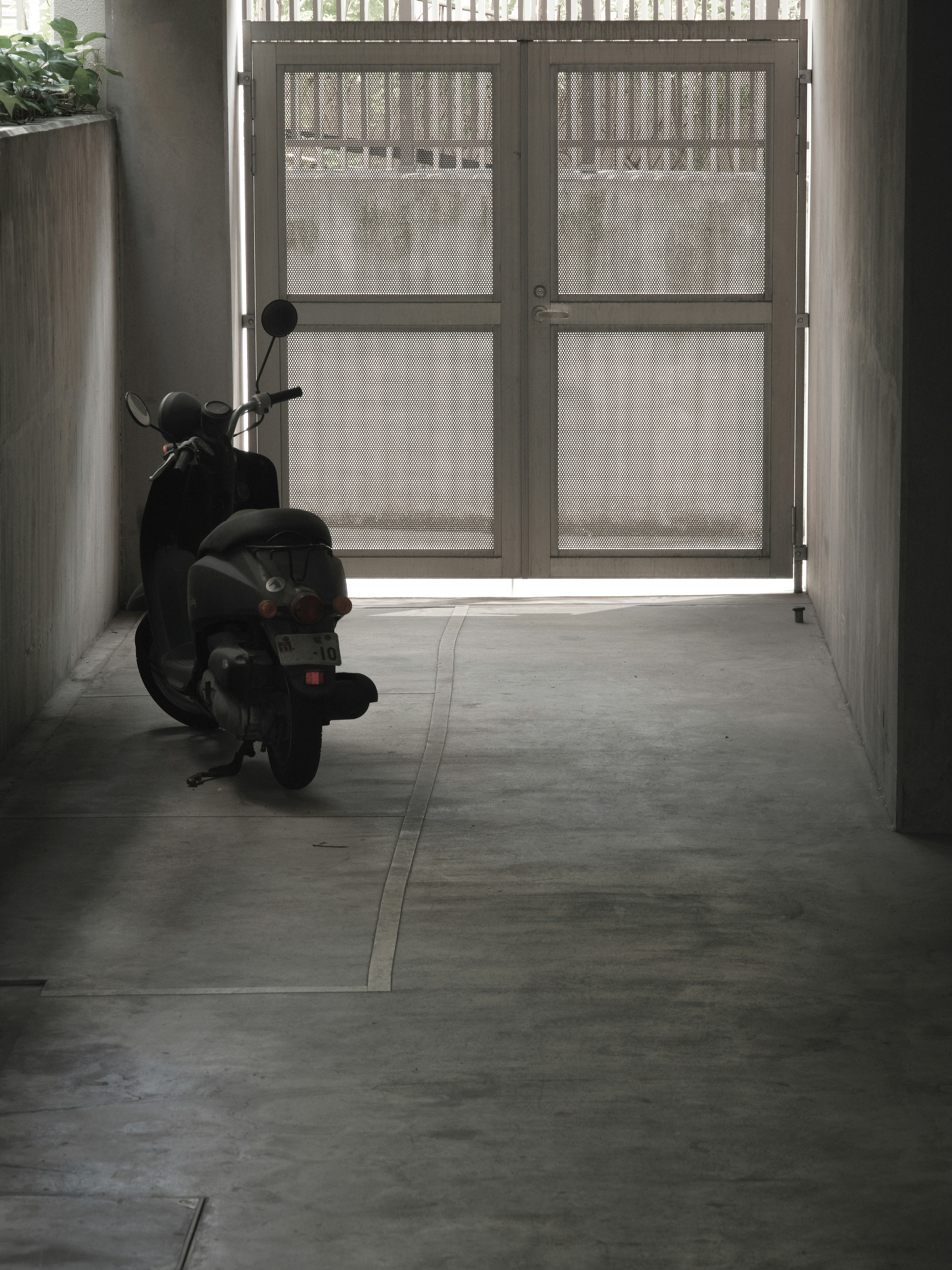 Scooter estacionado en un pasillo oscuro con luz que entra por una puerta