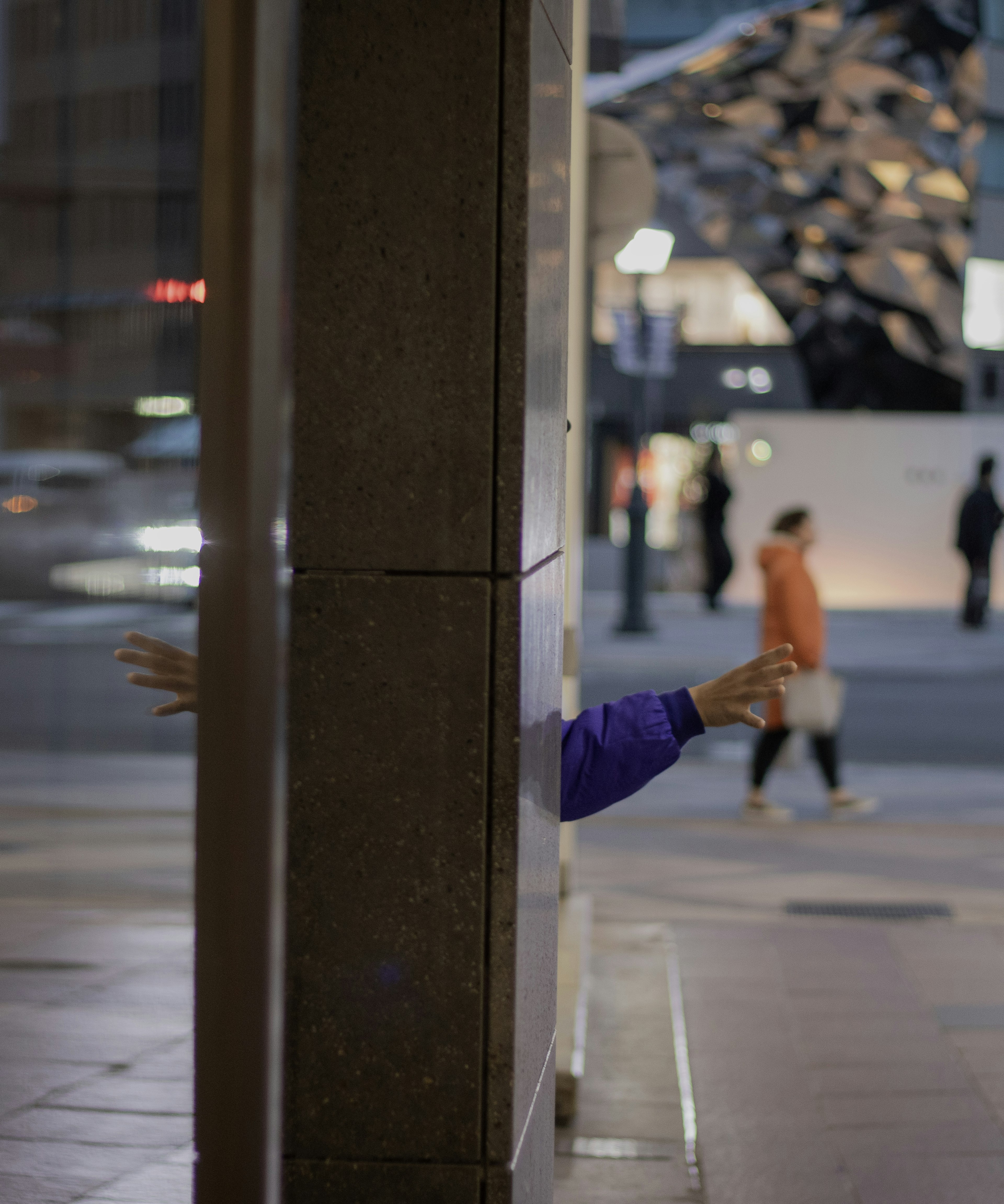 Una mano saliendo de una grieta en una pared en una ciudad de noche