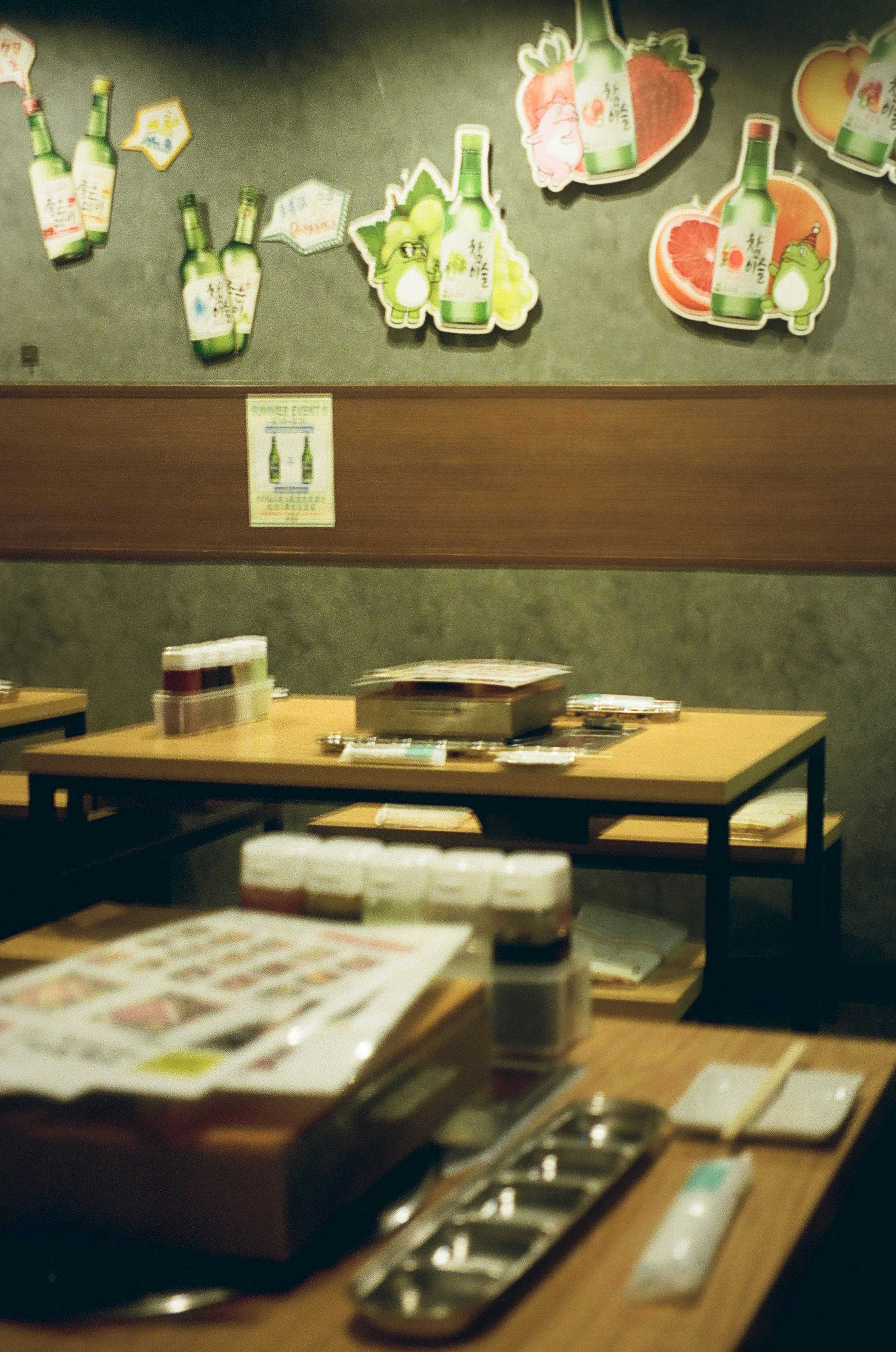 Interior de un izakaya con mesas y menús decorados con imágenes de comida y bebida en la pared