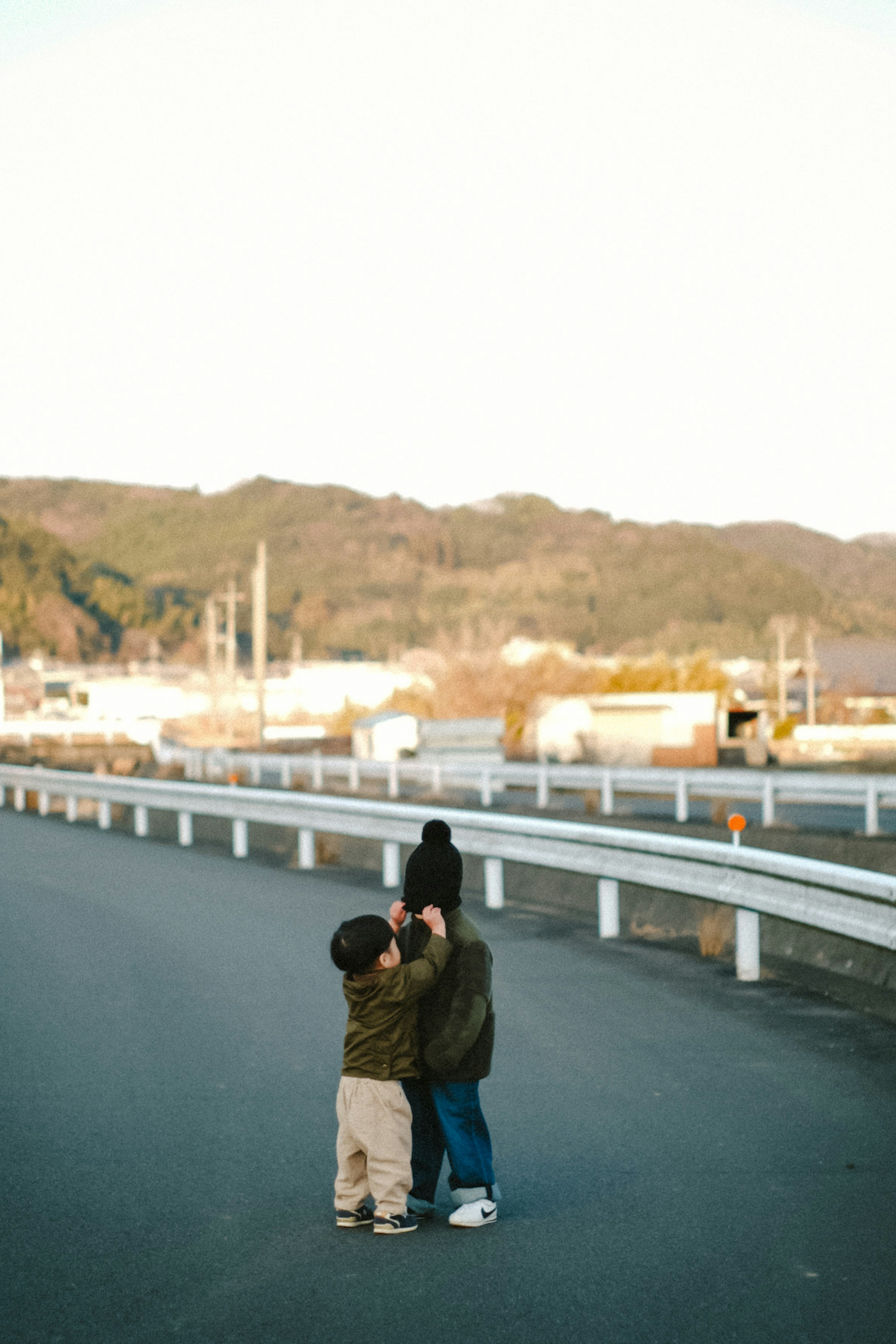 兩個孩子在馬路中間玩耍 背景是山和工廠