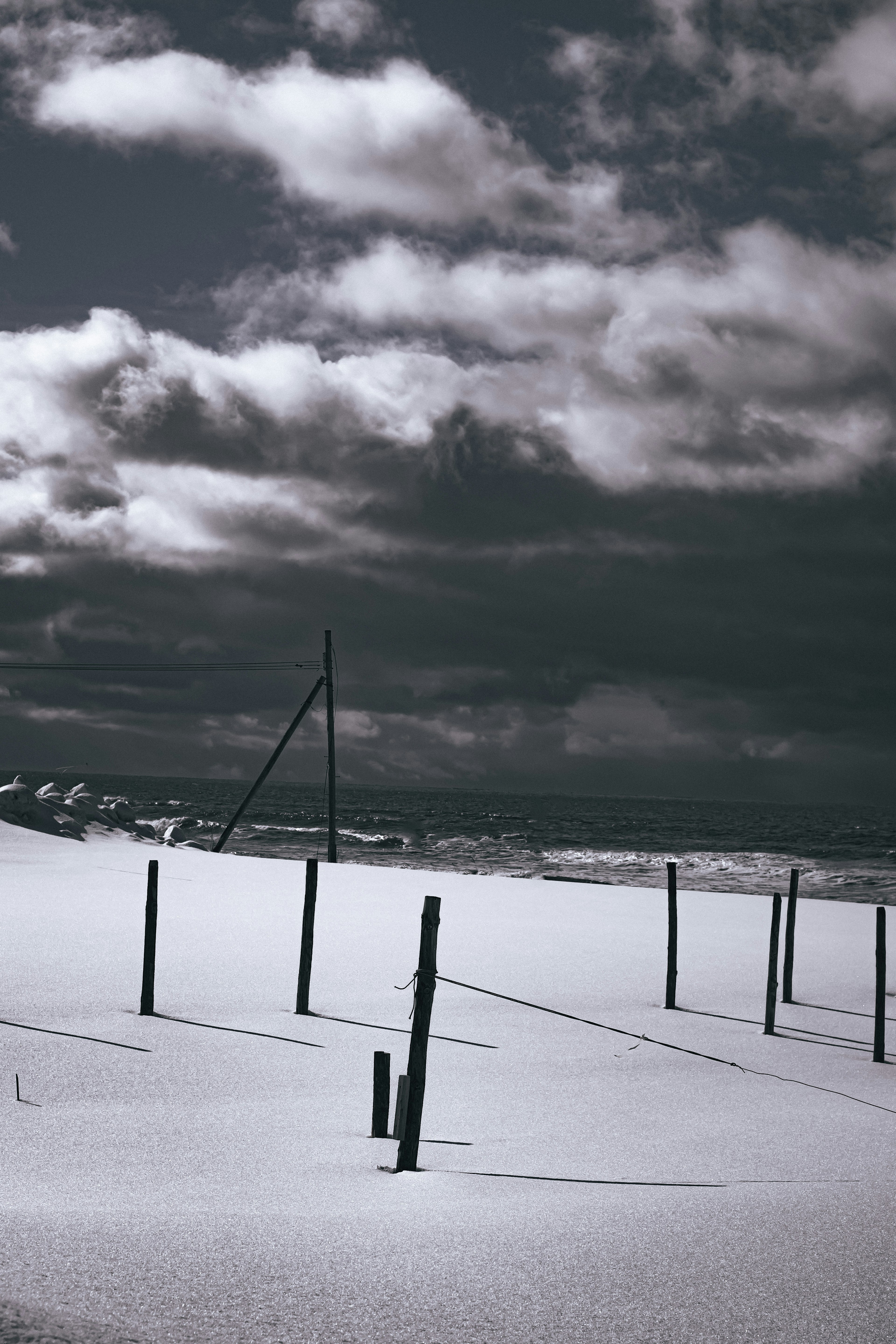 Paisaje cubierto de nieve con postes y cielo nublado