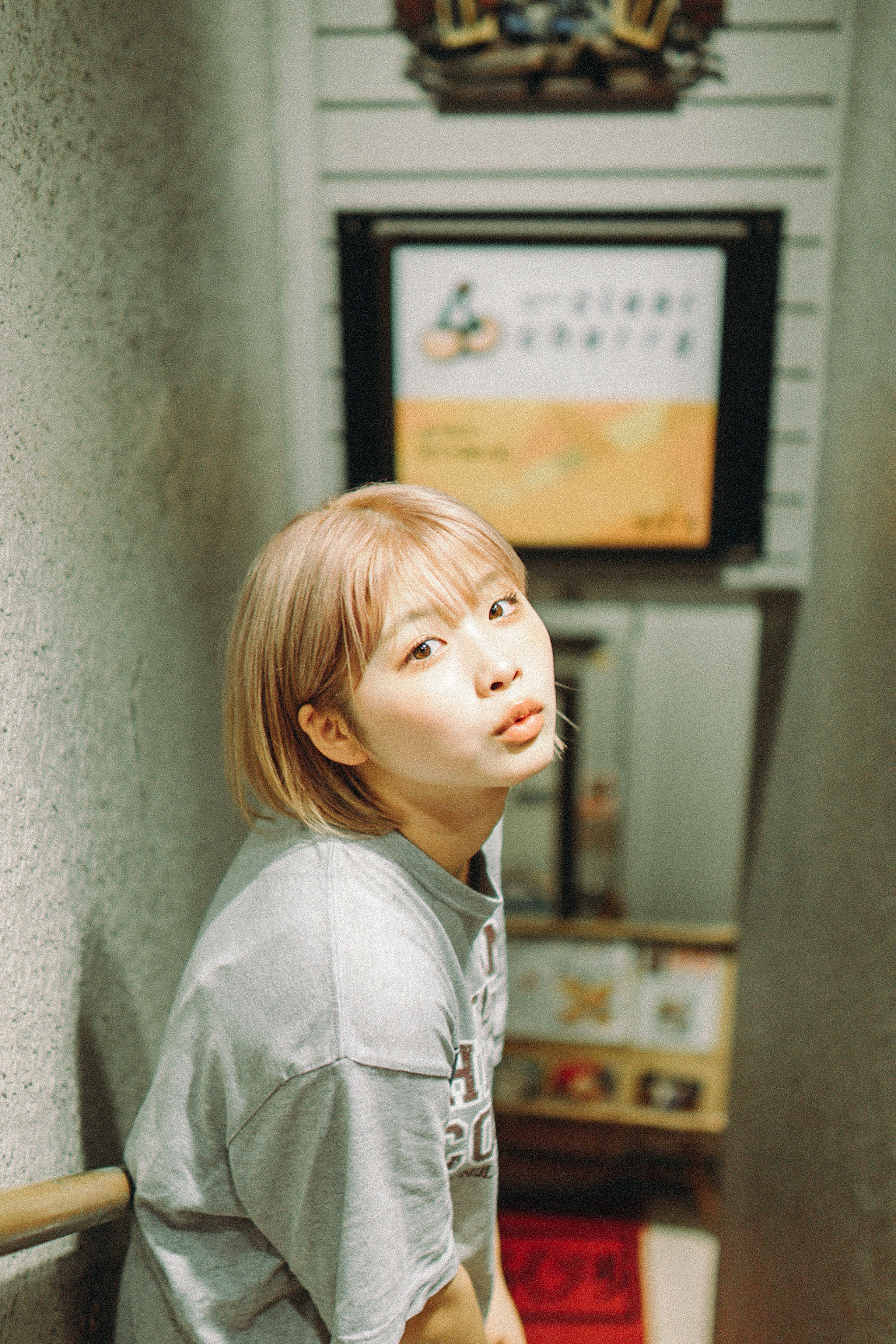 Side profile of a woman sitting on stairs with a background sign