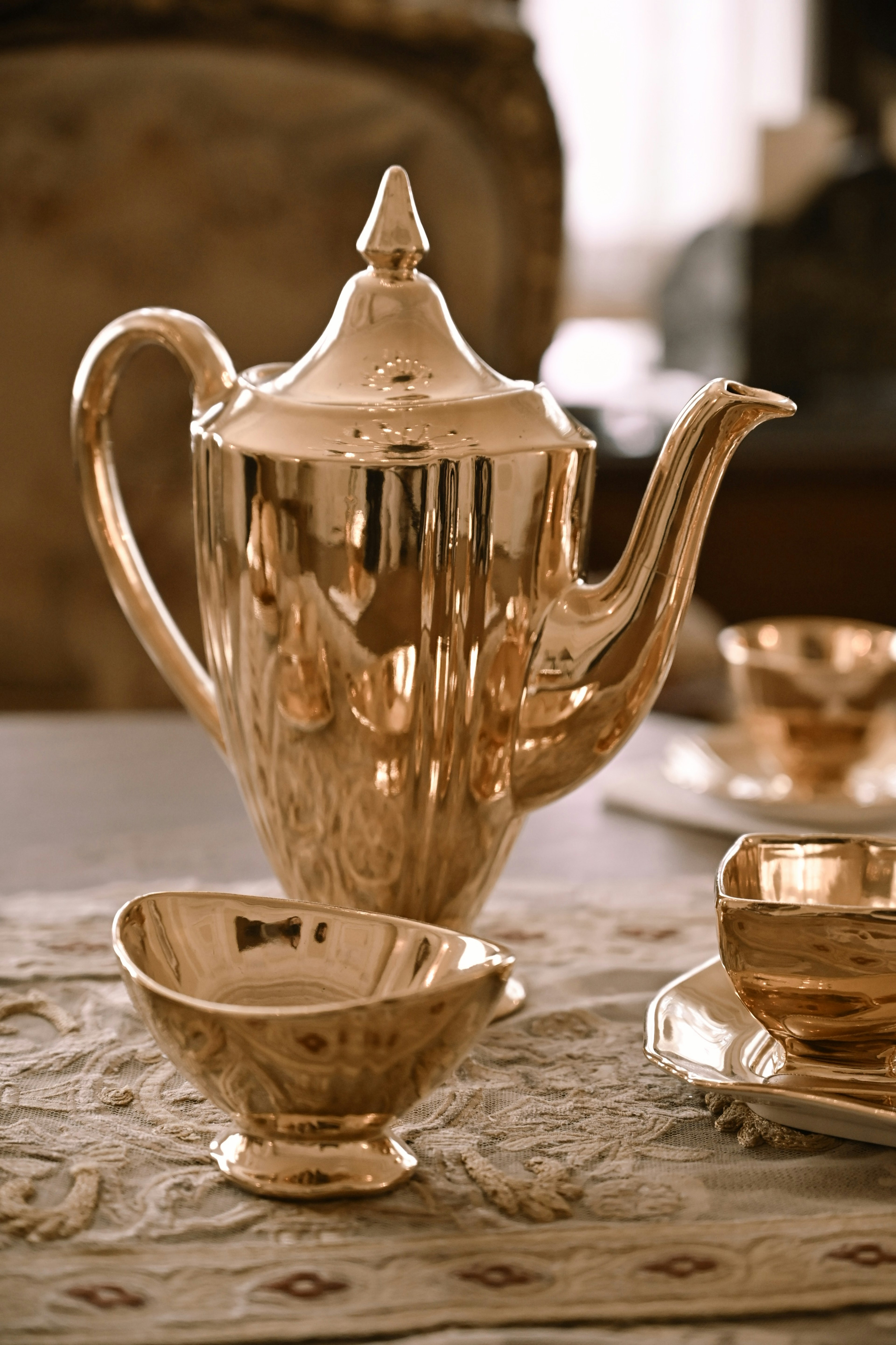 Elegant gold teapot with matching cups on a decorative table