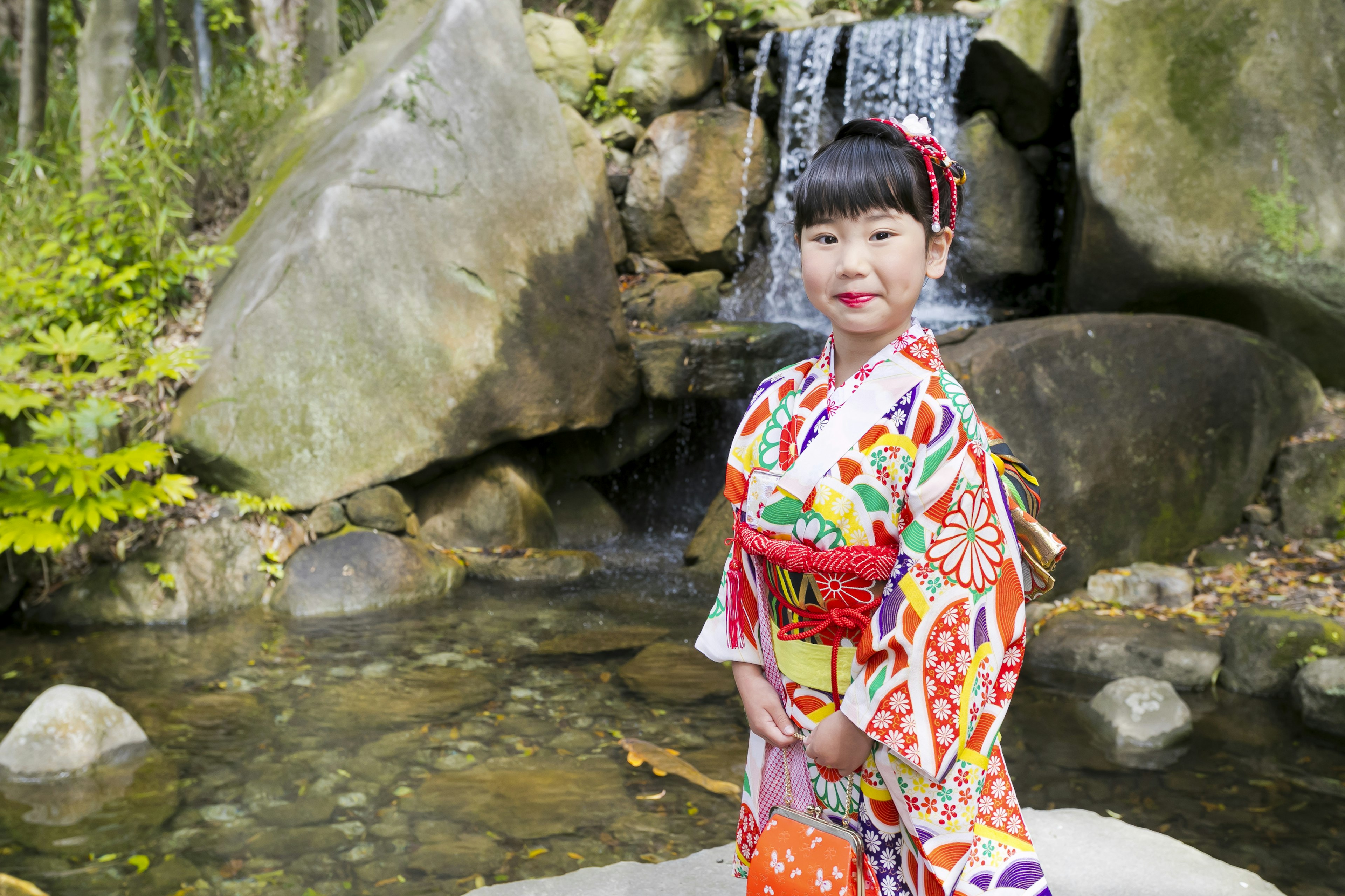 Niña con kimono colorido frente a una cascada