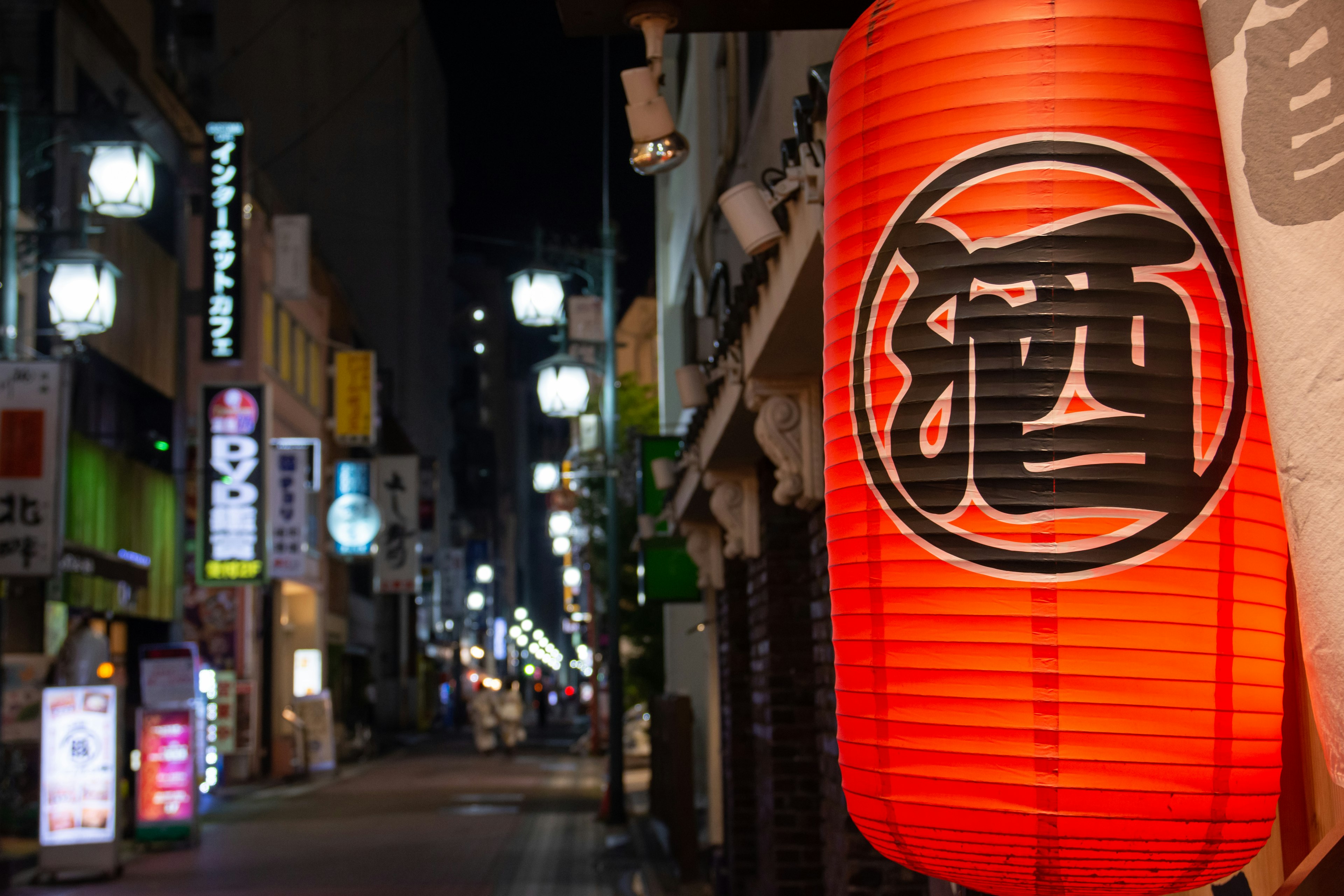 Red lantern illuminated at night with street lights in the background