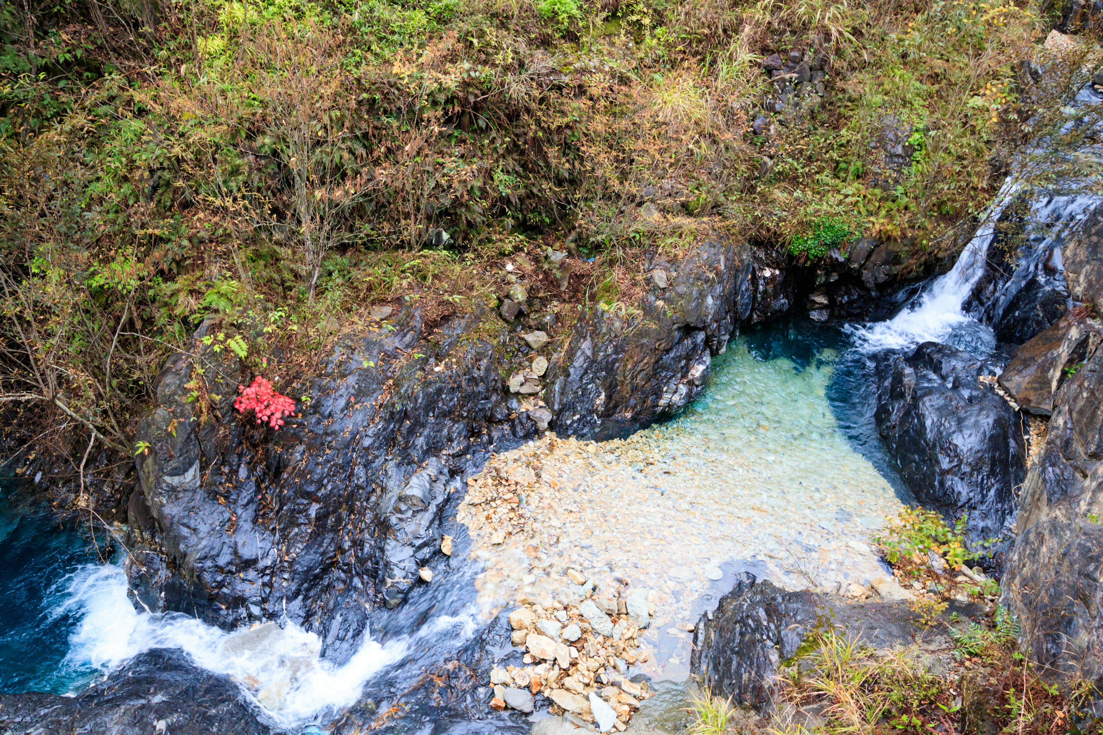 Pemandangan indah ngarai dengan air biru mengalir di antara batu dan pantai kecil berpasir