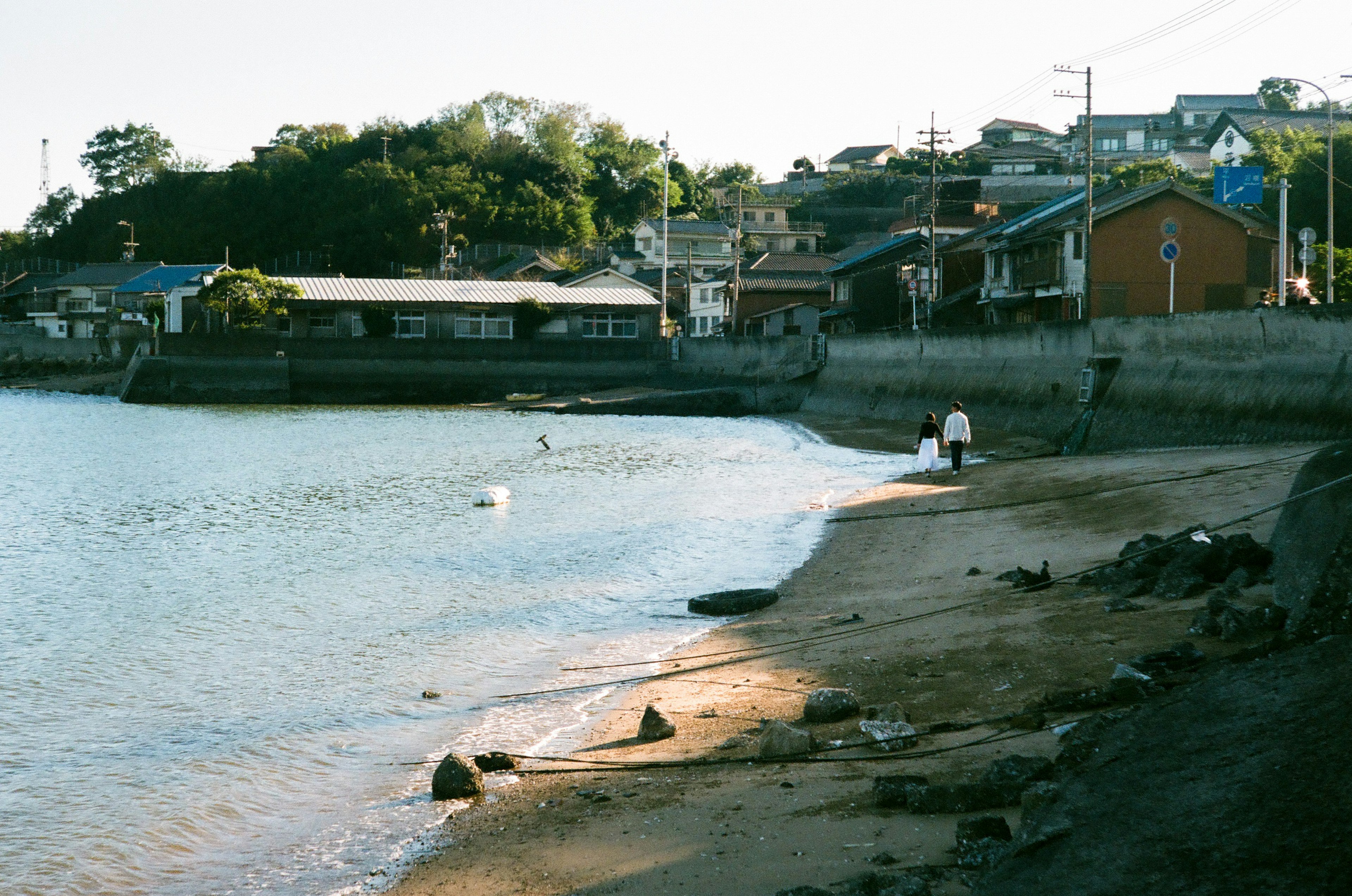 Vista escénica de un tranquilo pueblo costero con personas caminando por la playa