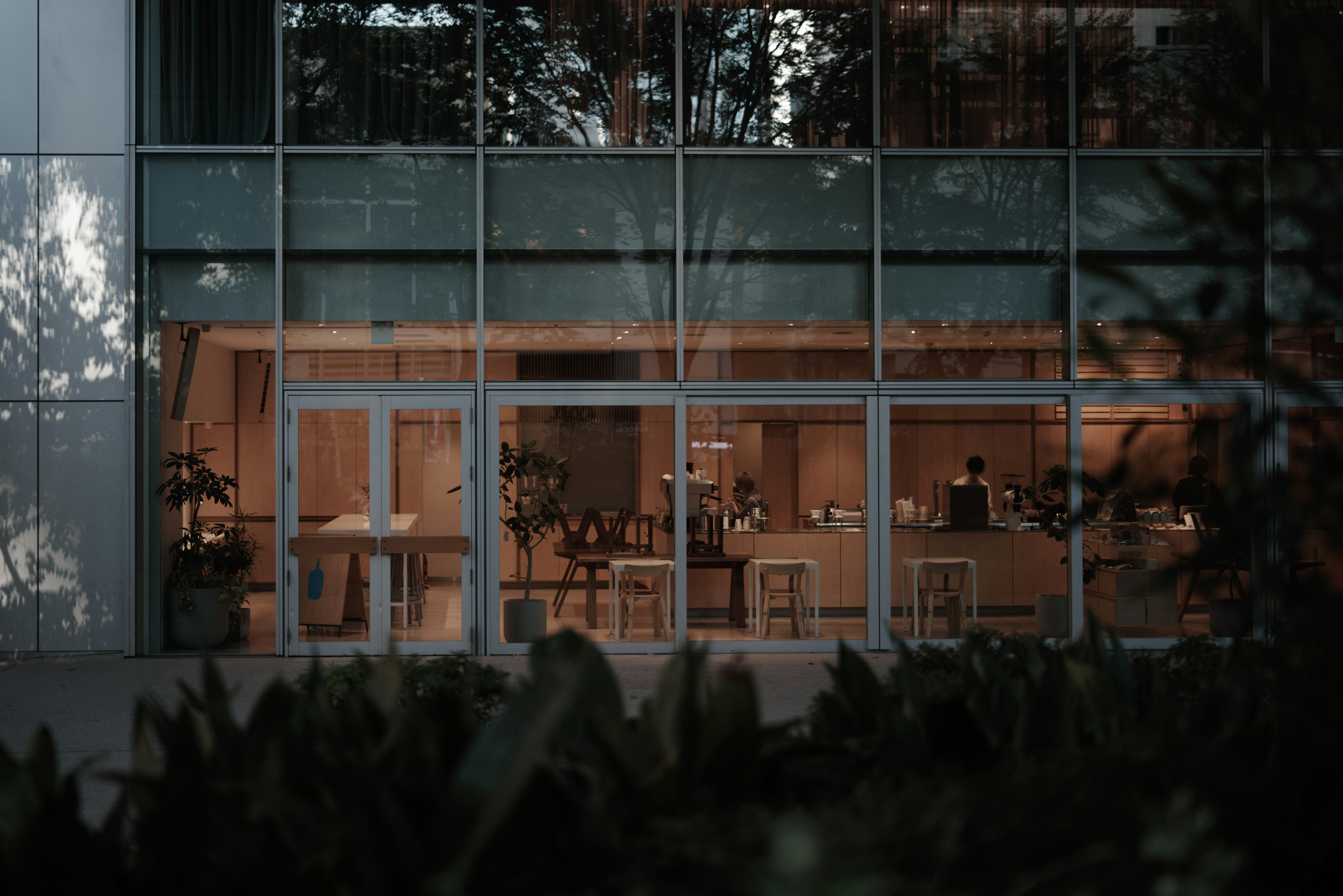 Vue d'un café moderne avec une ambiance décontractée visible à travers de grandes fenêtres en verre