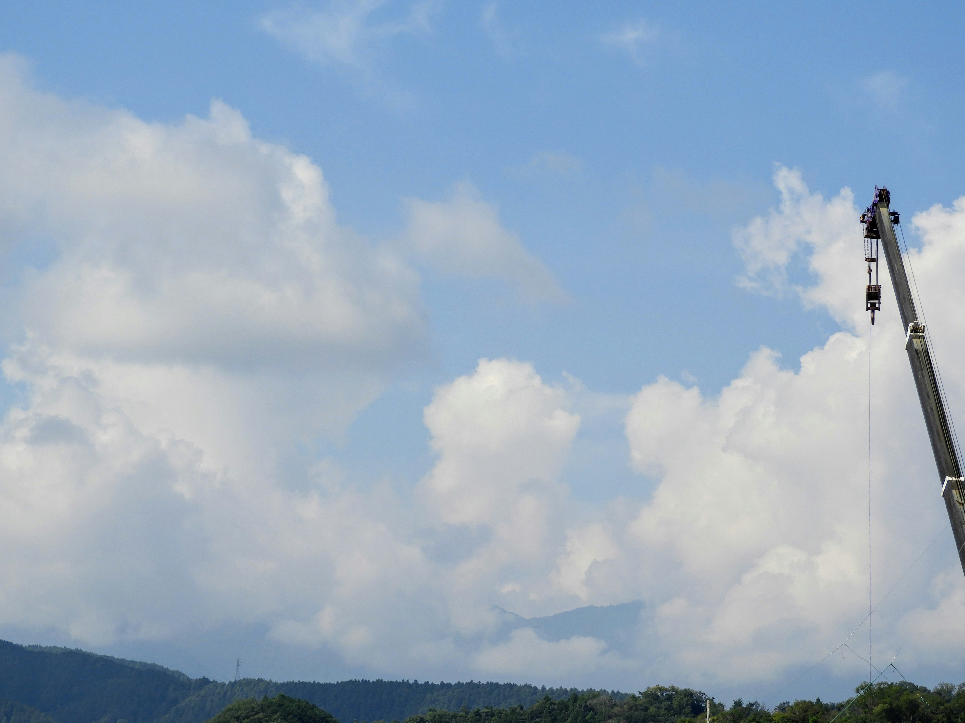 White clouds in a blue sky with a crane