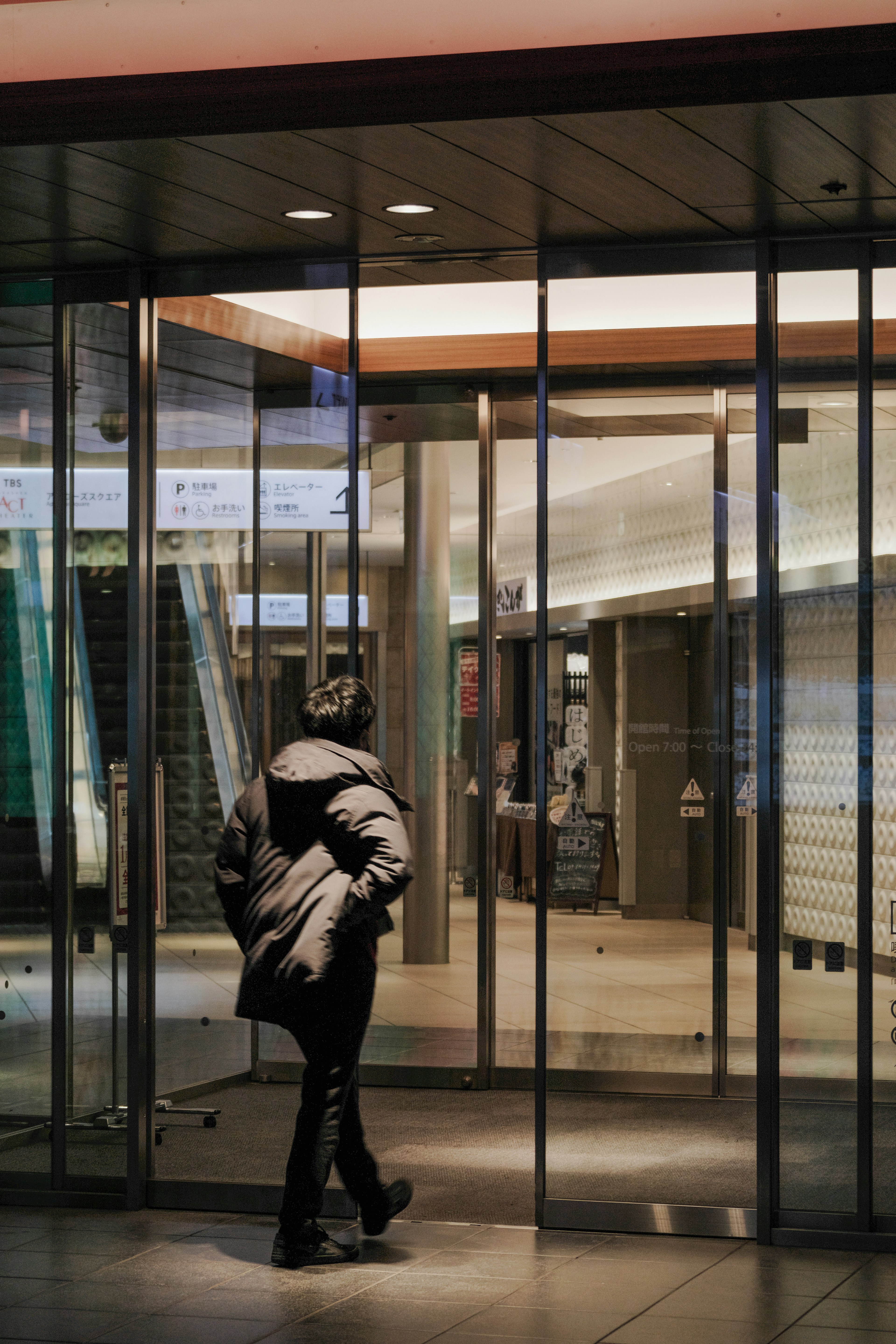 Une personne entrant par des portes en verre dans un intérieur de bâtiment moderne