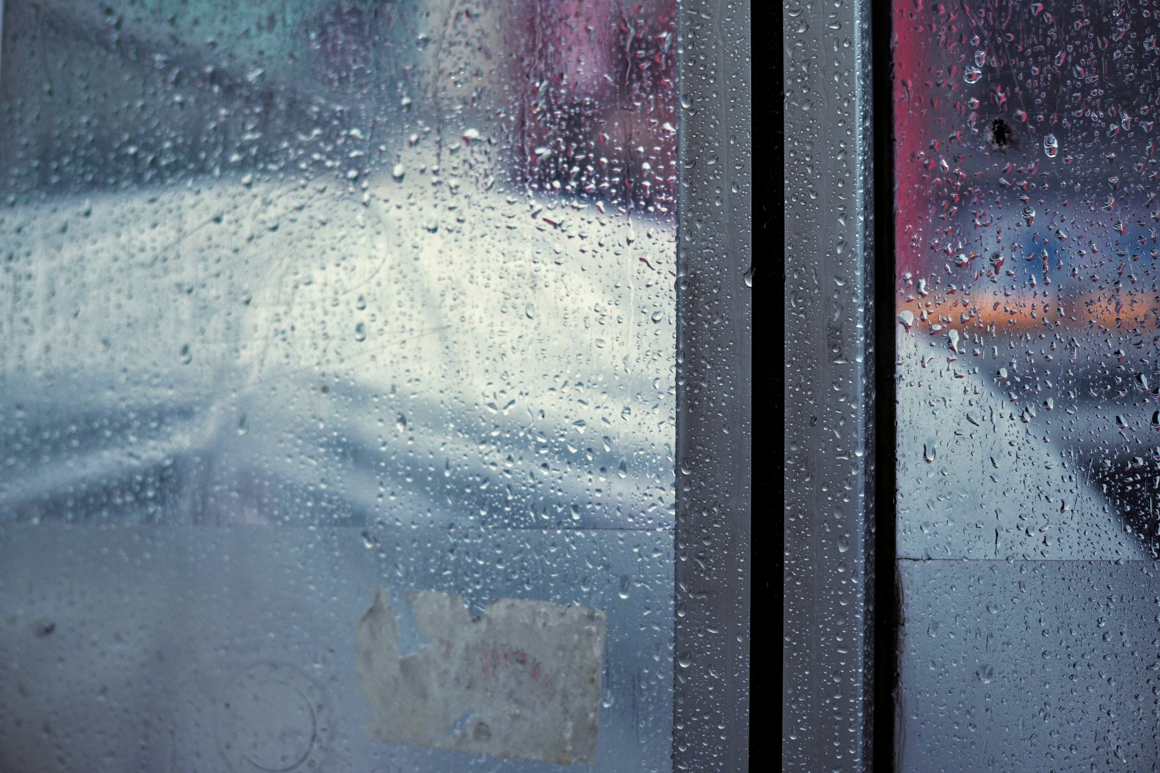 Vue floue à travers une fenêtre couverte de gouttes de pluie